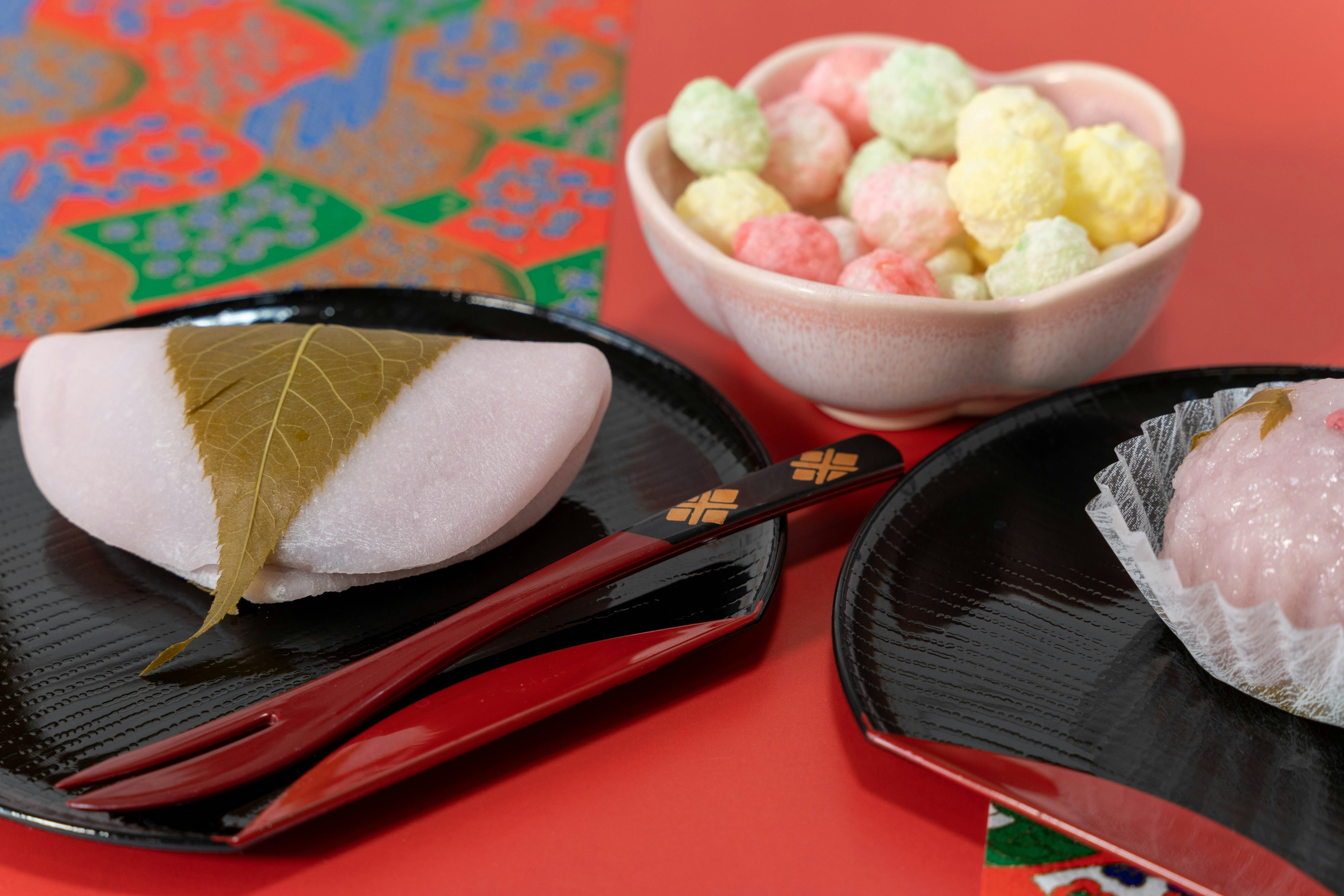 Zwei schwarze Teller mit traditionellen japanischen Süßigkeiten und bunten Bonbons