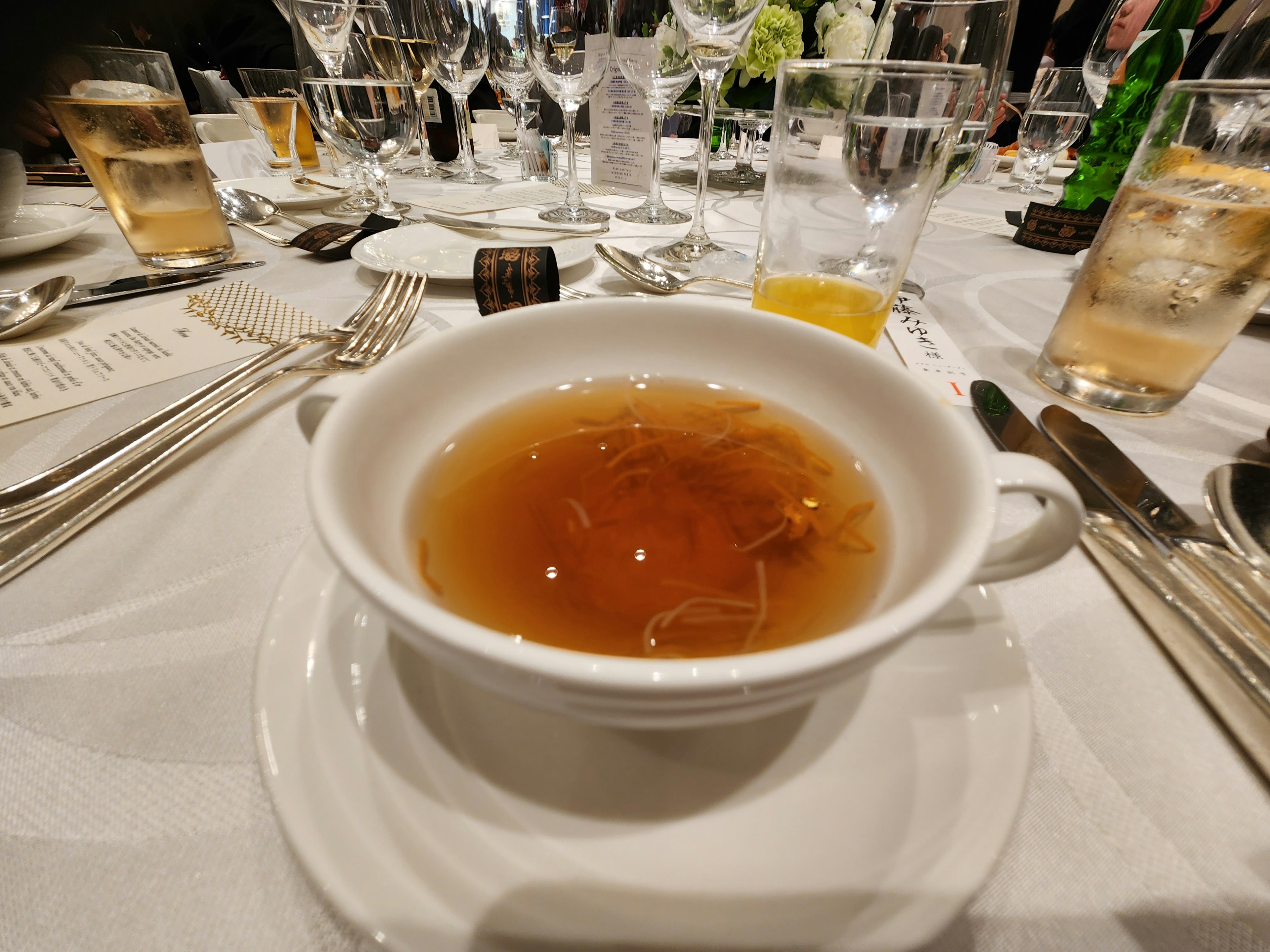 A warm cup of soup served on a white plate at a dining table