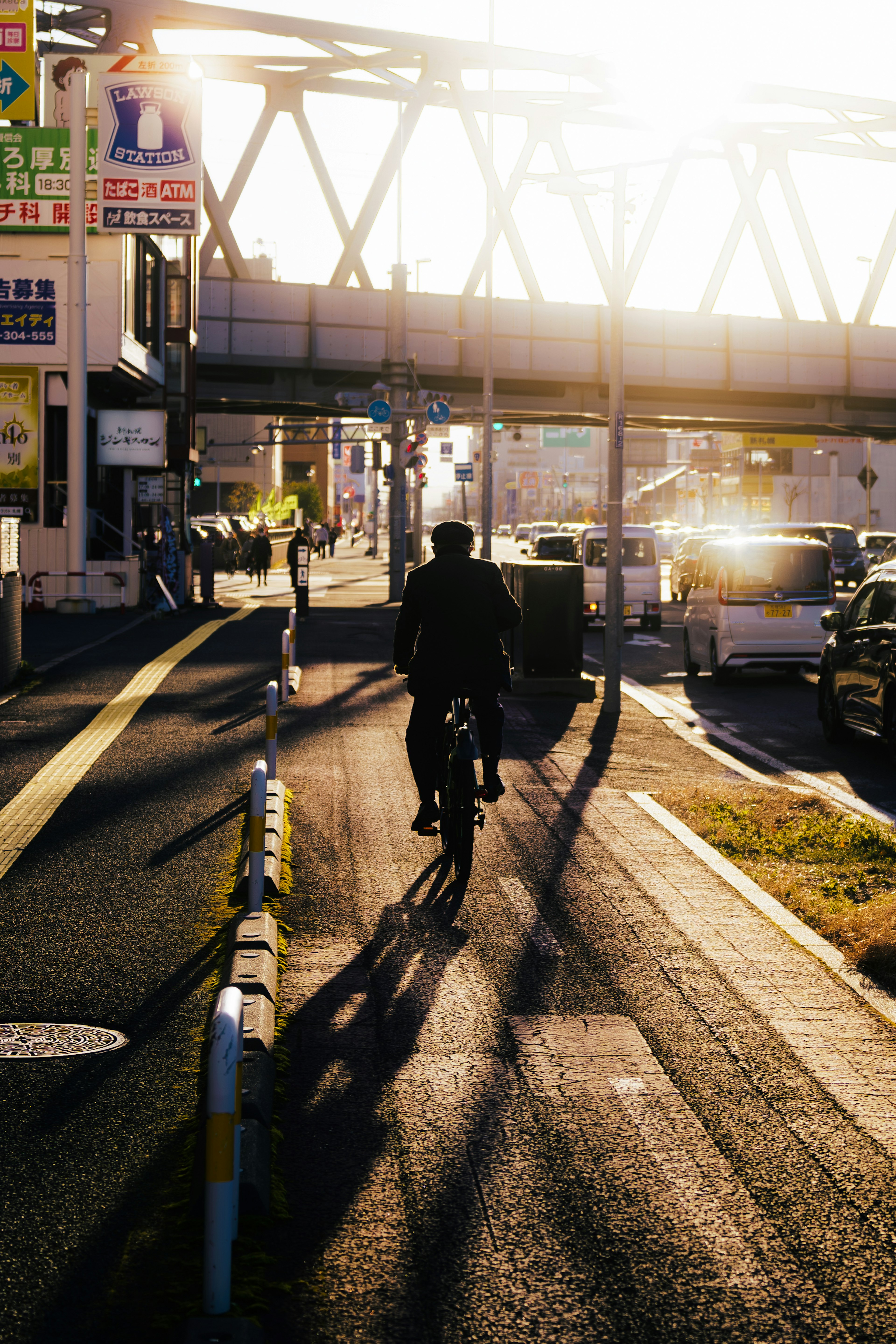 Silhouette di una persona in bicicletta al tramonto con paesaggio urbano