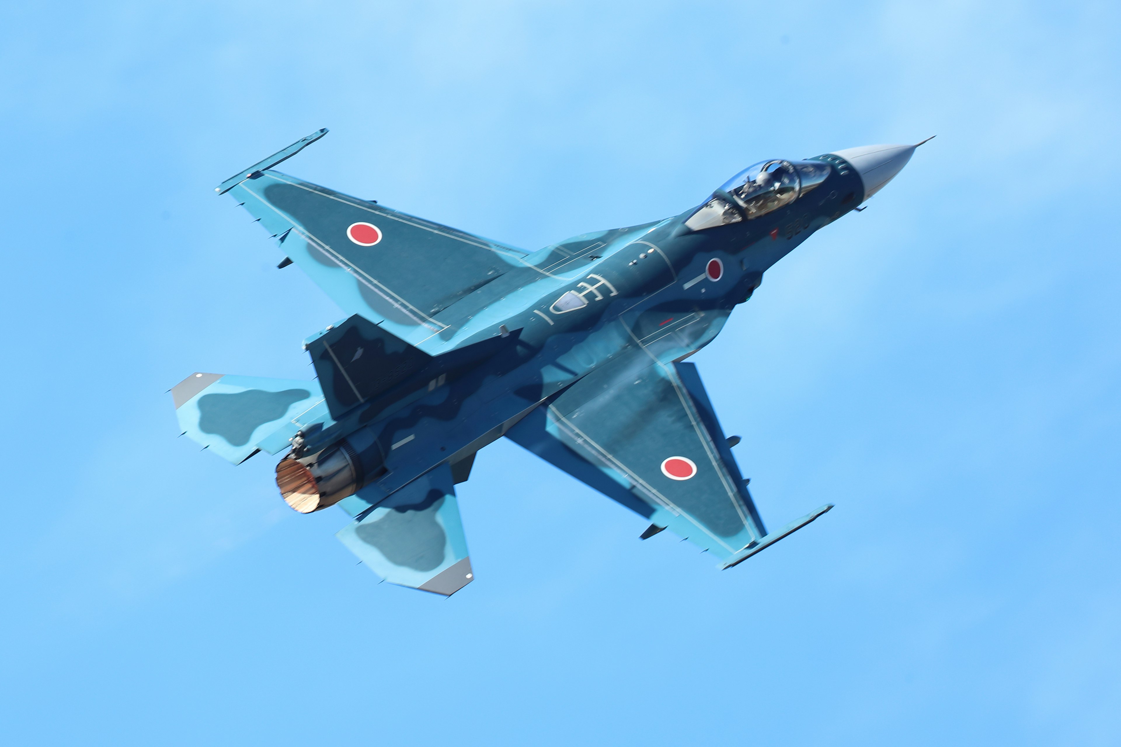 A blue fighter jet flying in the sky