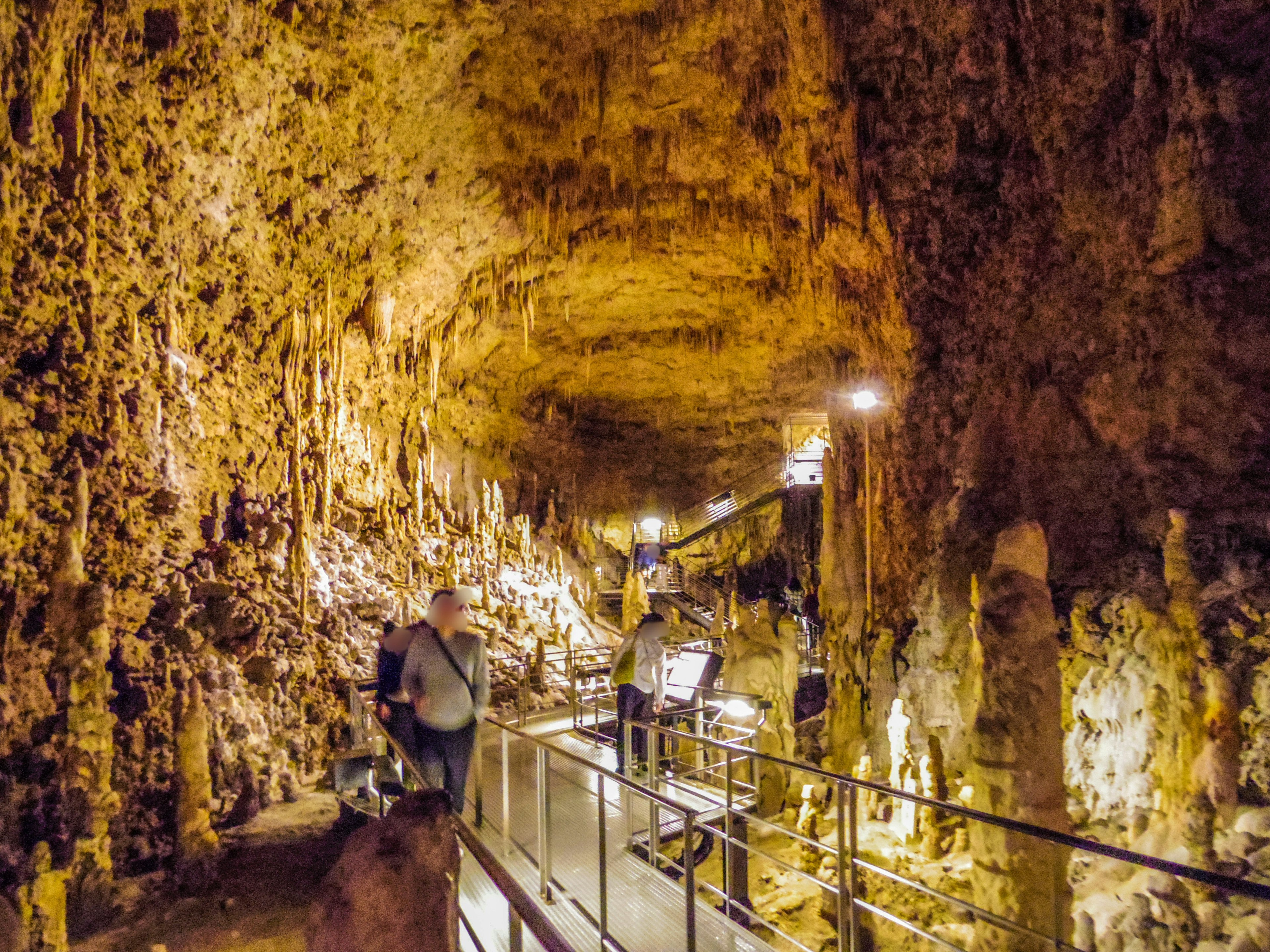 Turistas explorando una cueva con paredes de piedra caliza iluminadas