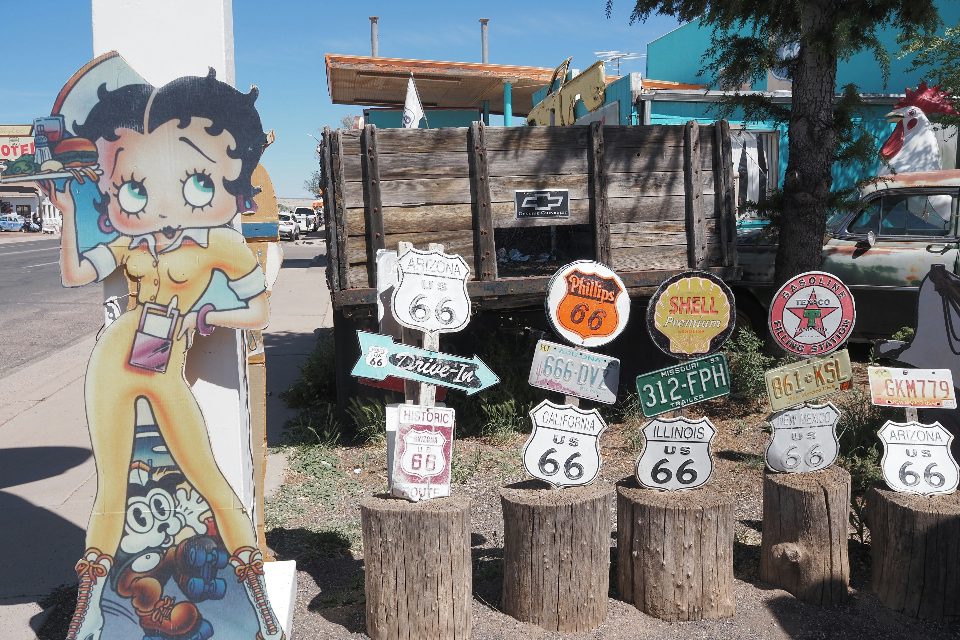 Panneau avec le personnage de Betty Boop et des panneaux de la Route 66 sur des troncs en bois