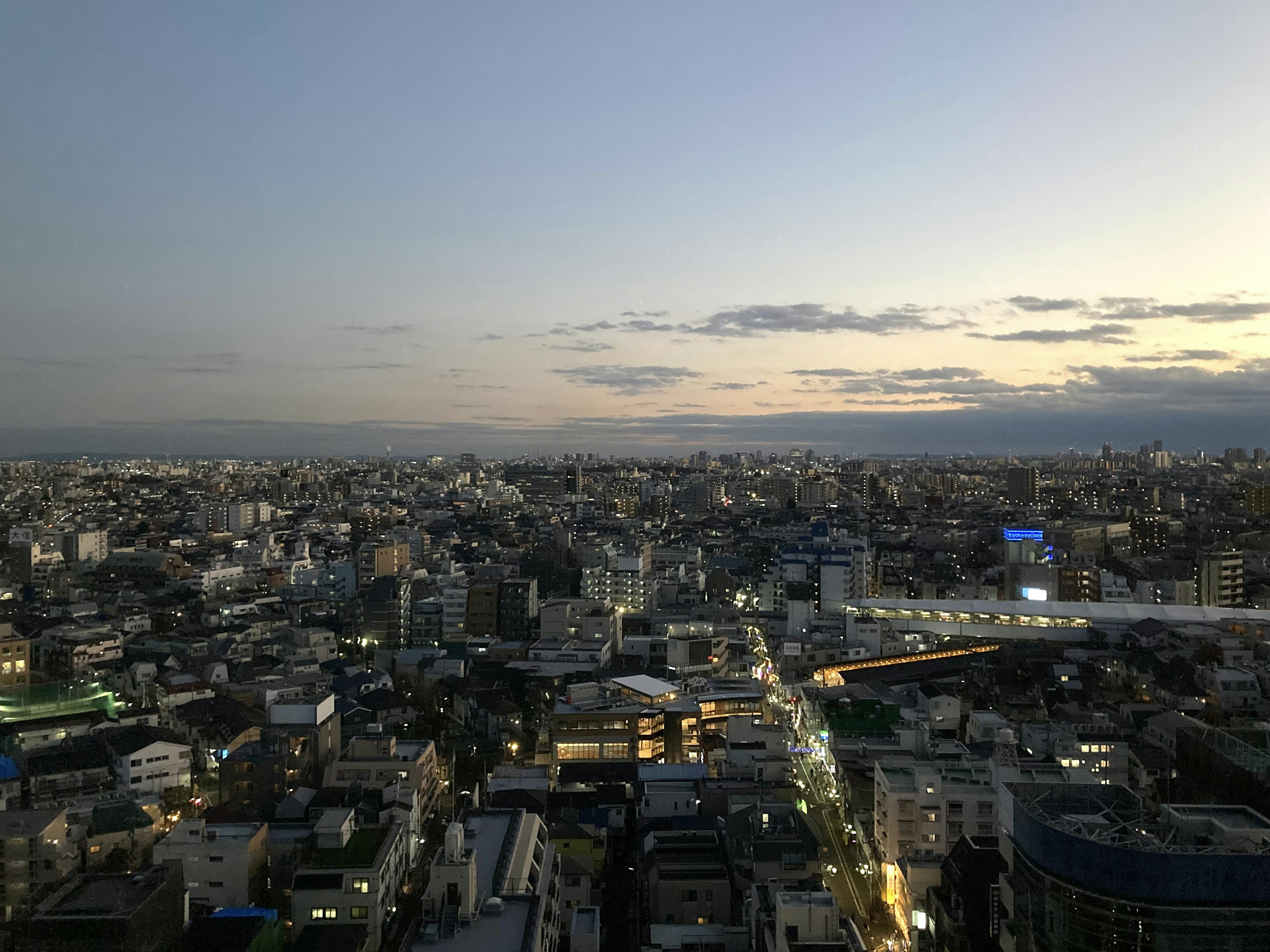 Panoramic view of a city at dusk featuring bright streetlights and residential buildings