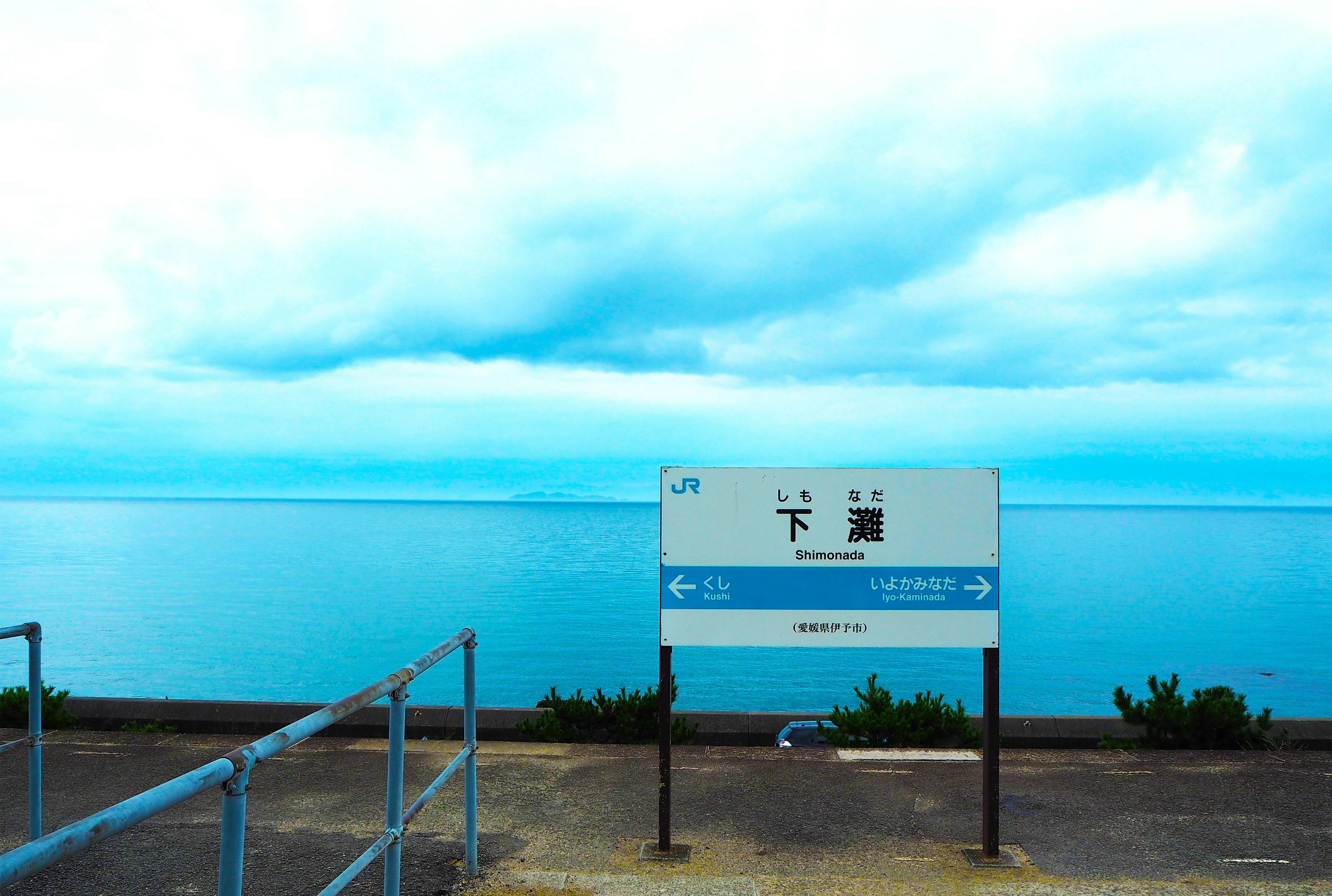 Sign for Shimonoseki station with blue sea and cloudy sky