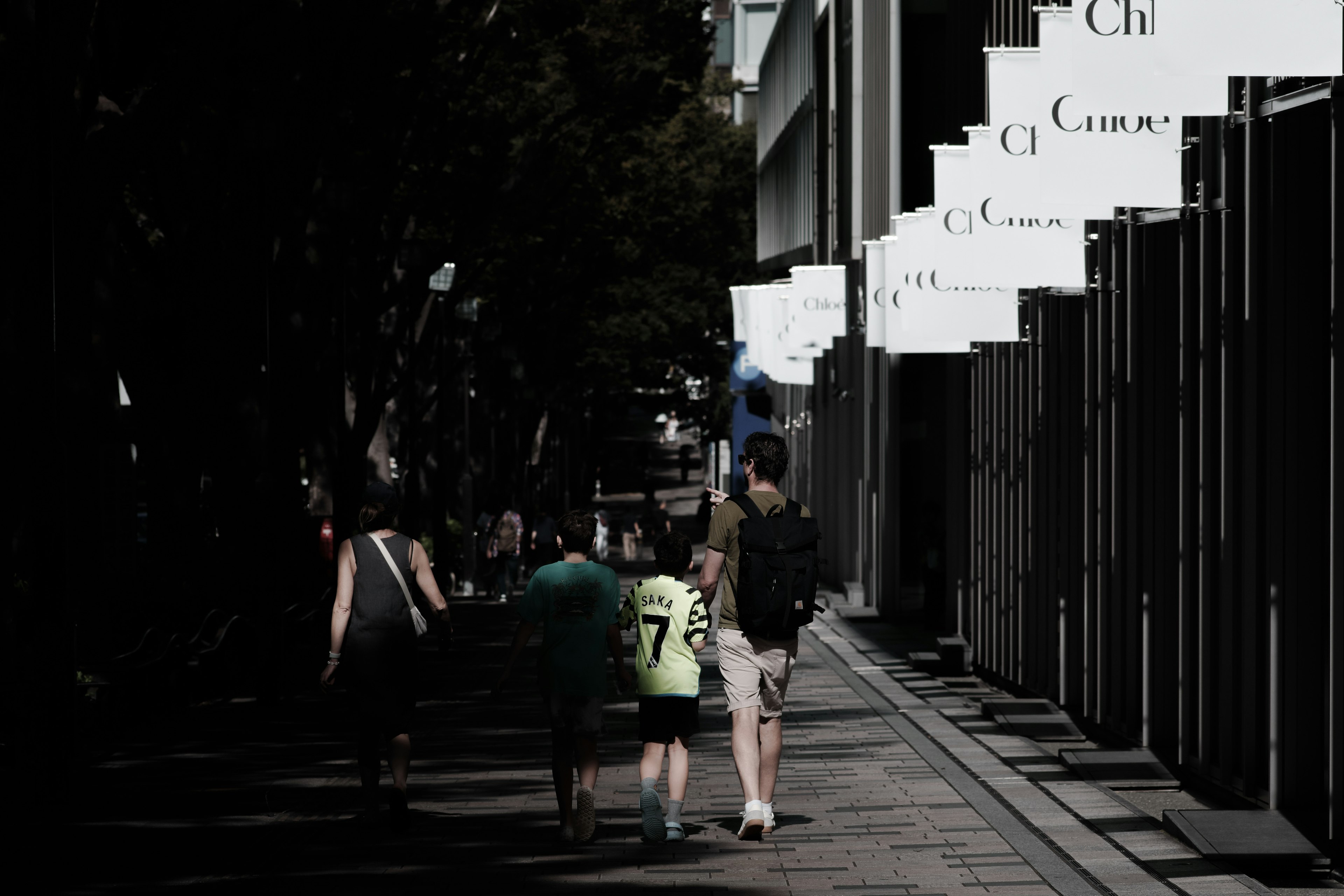 Silhouette of a family walking down a street with shop signs