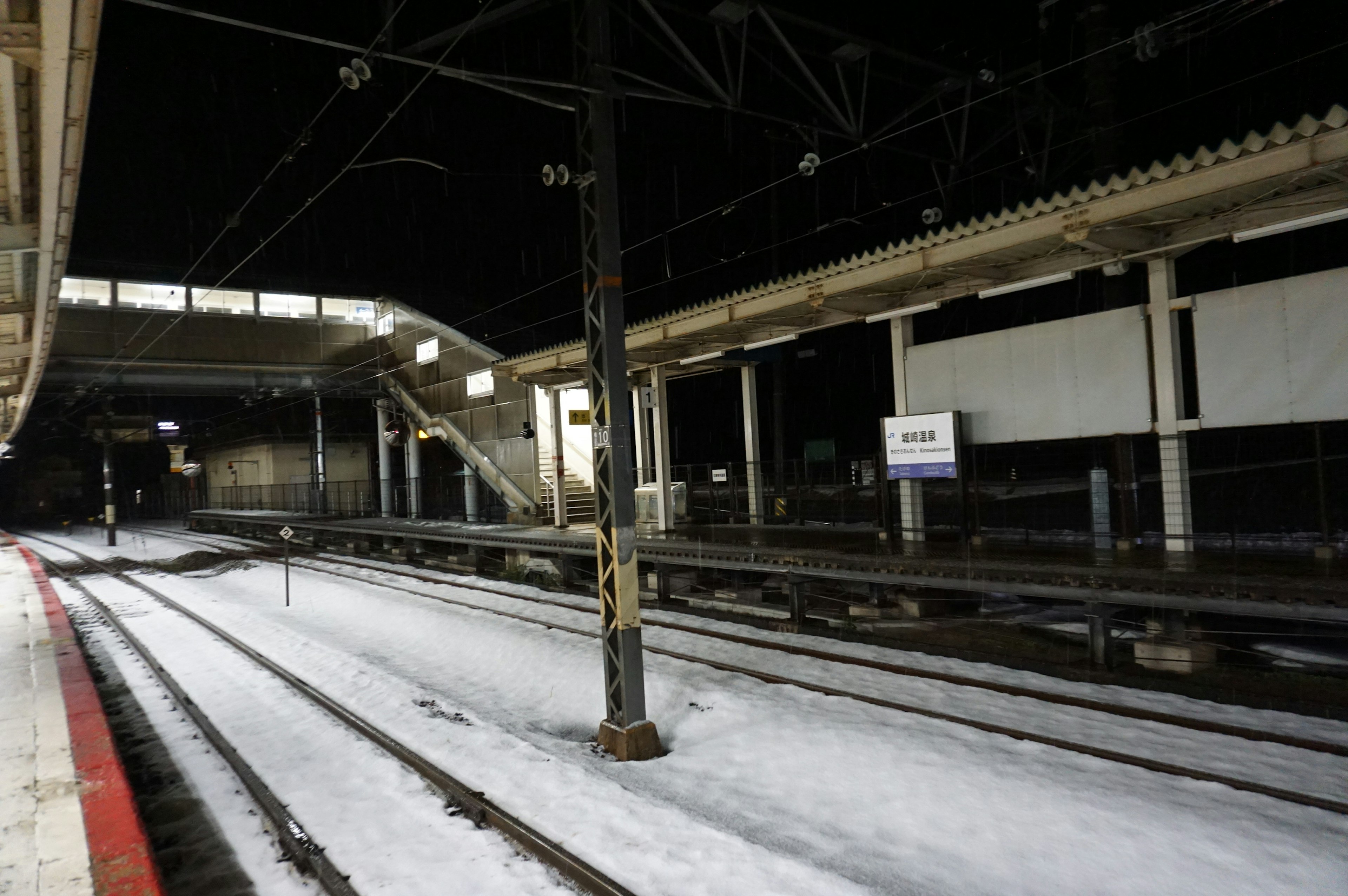 雪の積もった駅のプラットフォームと線路の風景