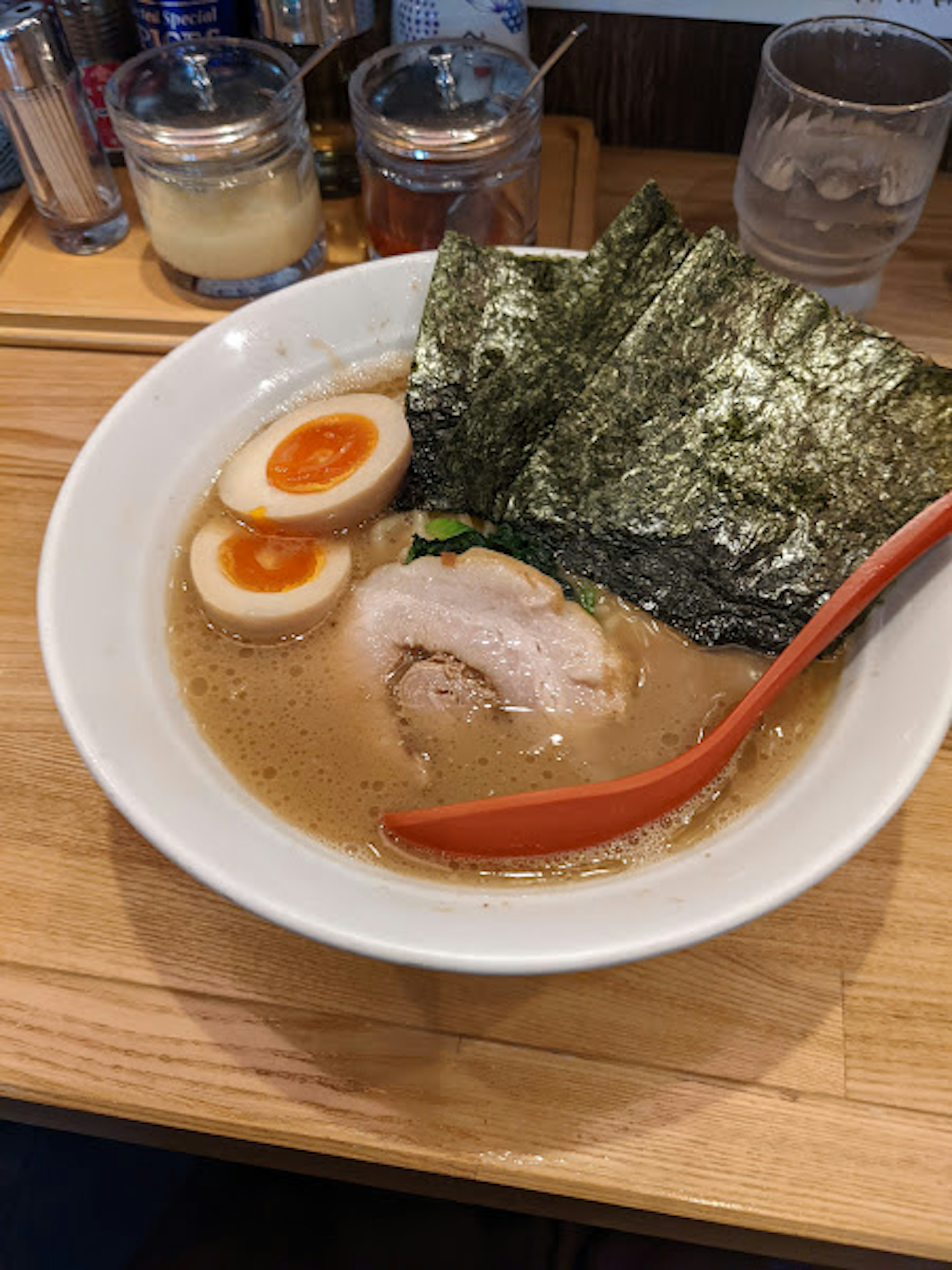 Semangkuk ramen yang lezat dengan daging babi iris dan telur setengah matang dihiasi dengan rumput laut