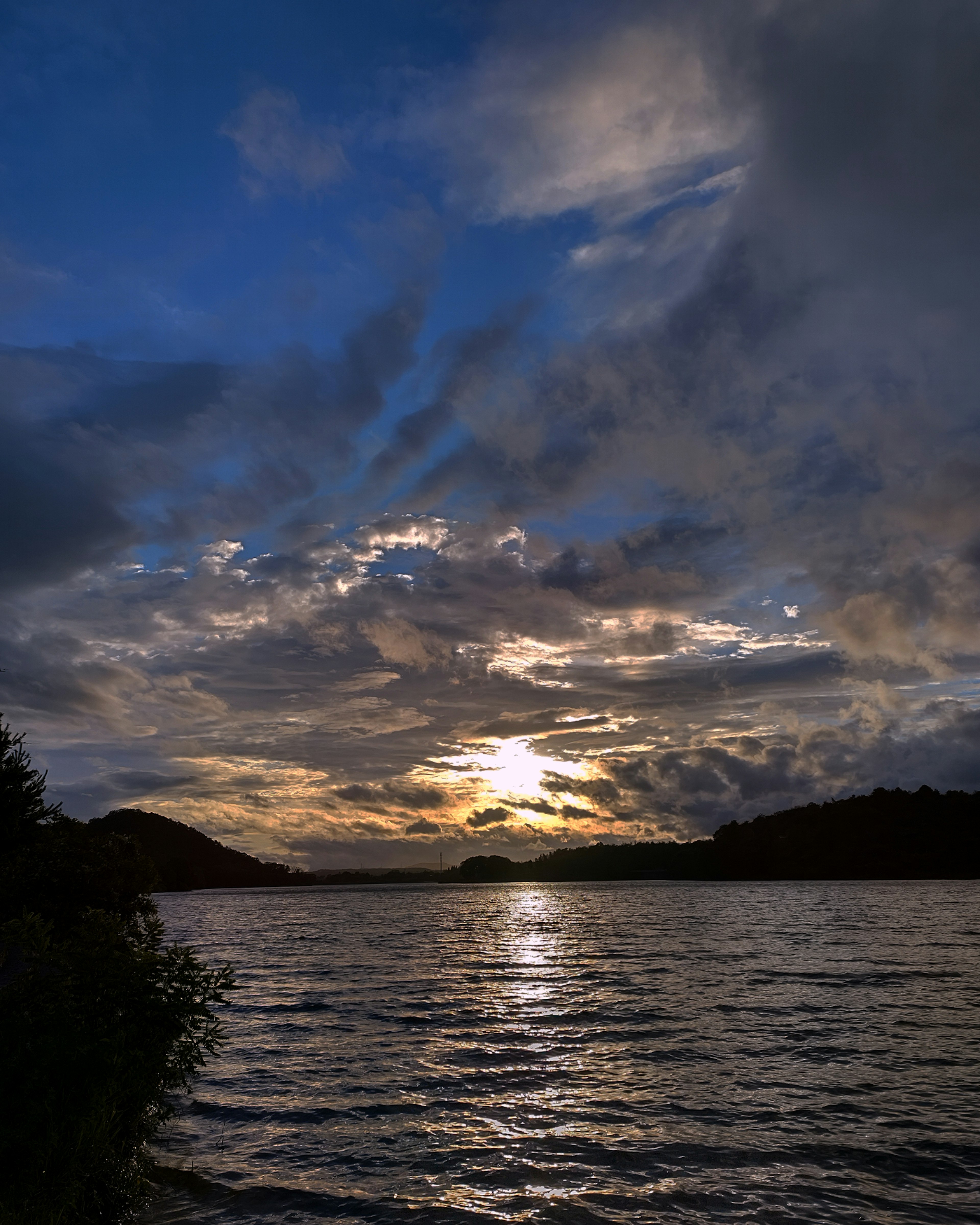 Vue pittoresque d'un lac au coucher du soleil avec des nuages dramatiques et un ciel bleu