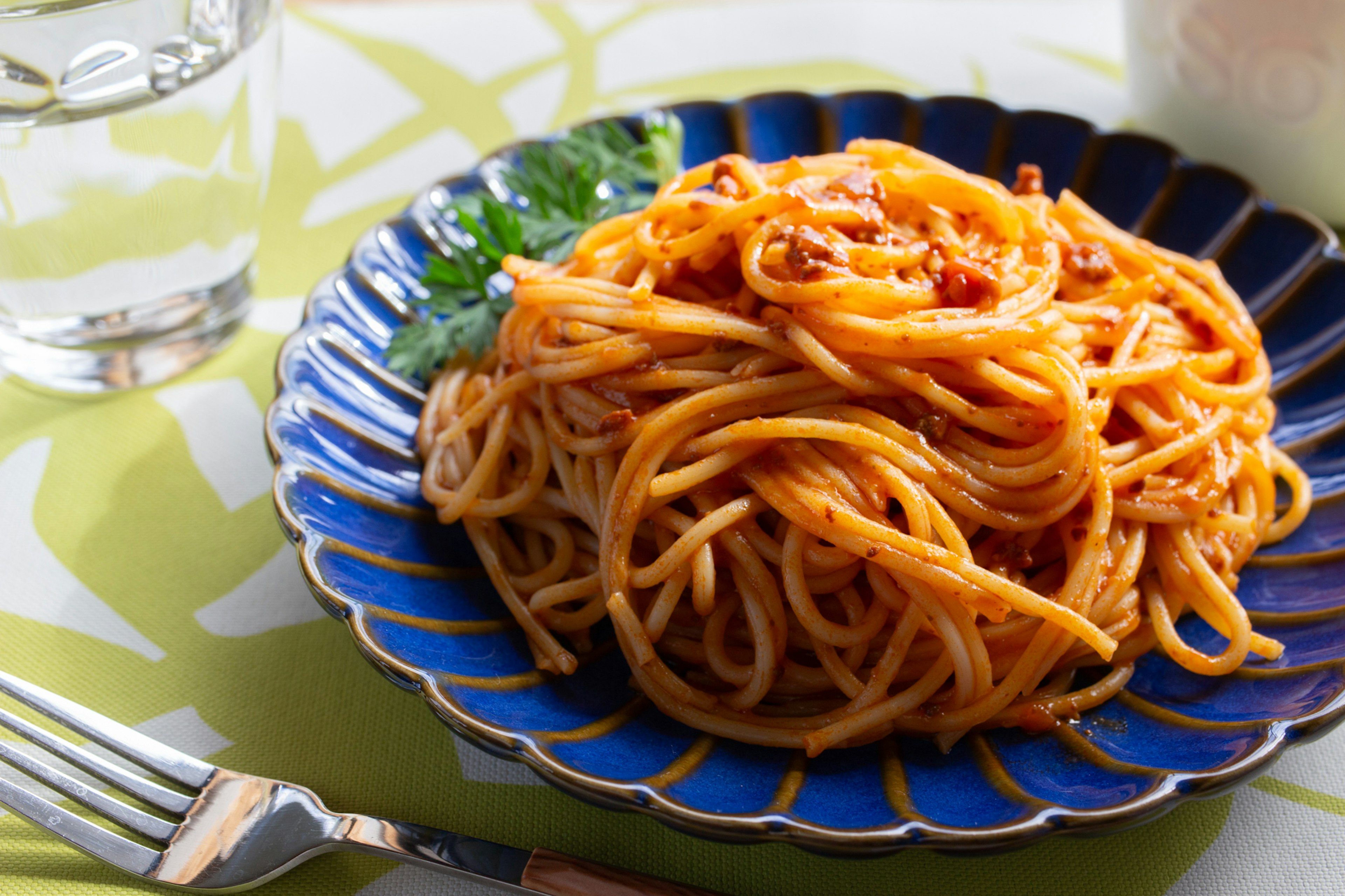 Spaghetti mit Tomatensauce auf einem blauen Teller serviert