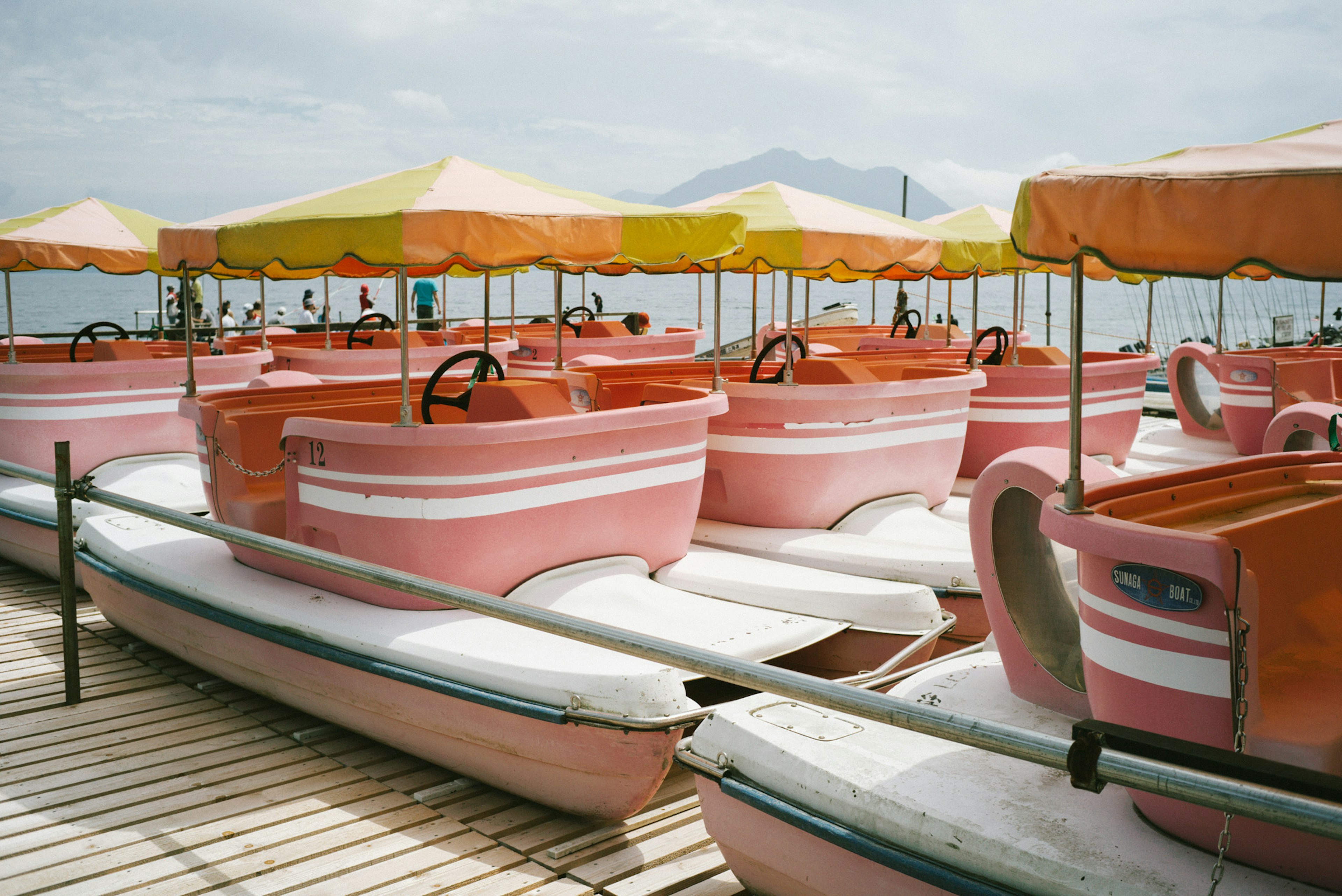 Colorful paddle boats with umbrellas at a lakeside