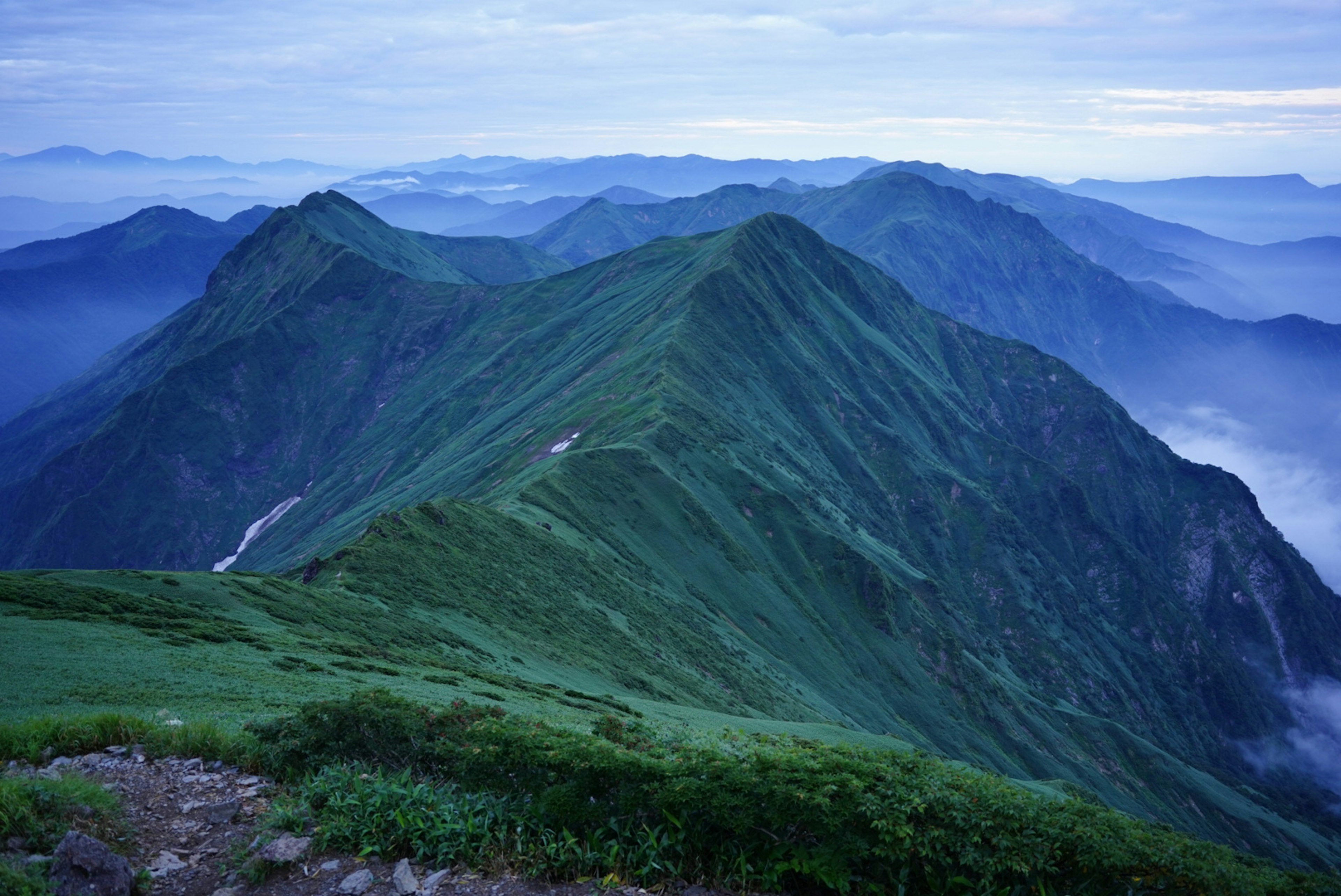 青い山々が連なる風景 緑の草原と霧に包まれた谷