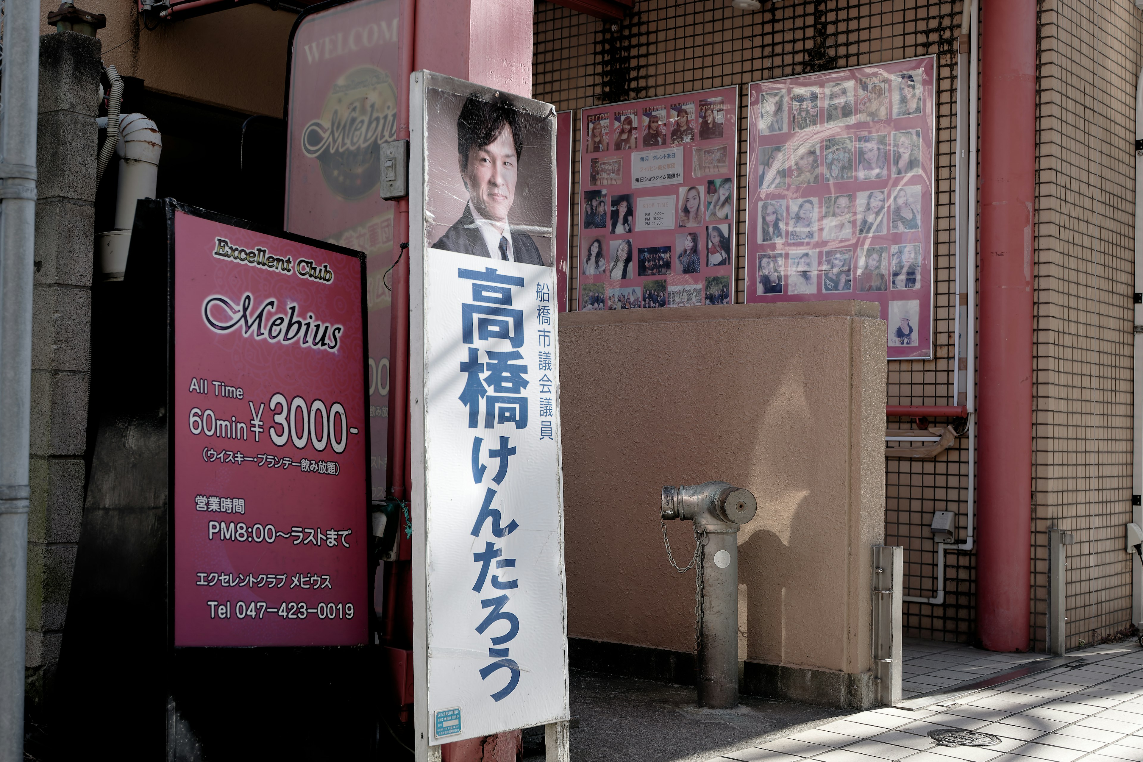 Ladenfront mit einem Schild, das ein Foto eines Mannes und japanischen Text zeigt