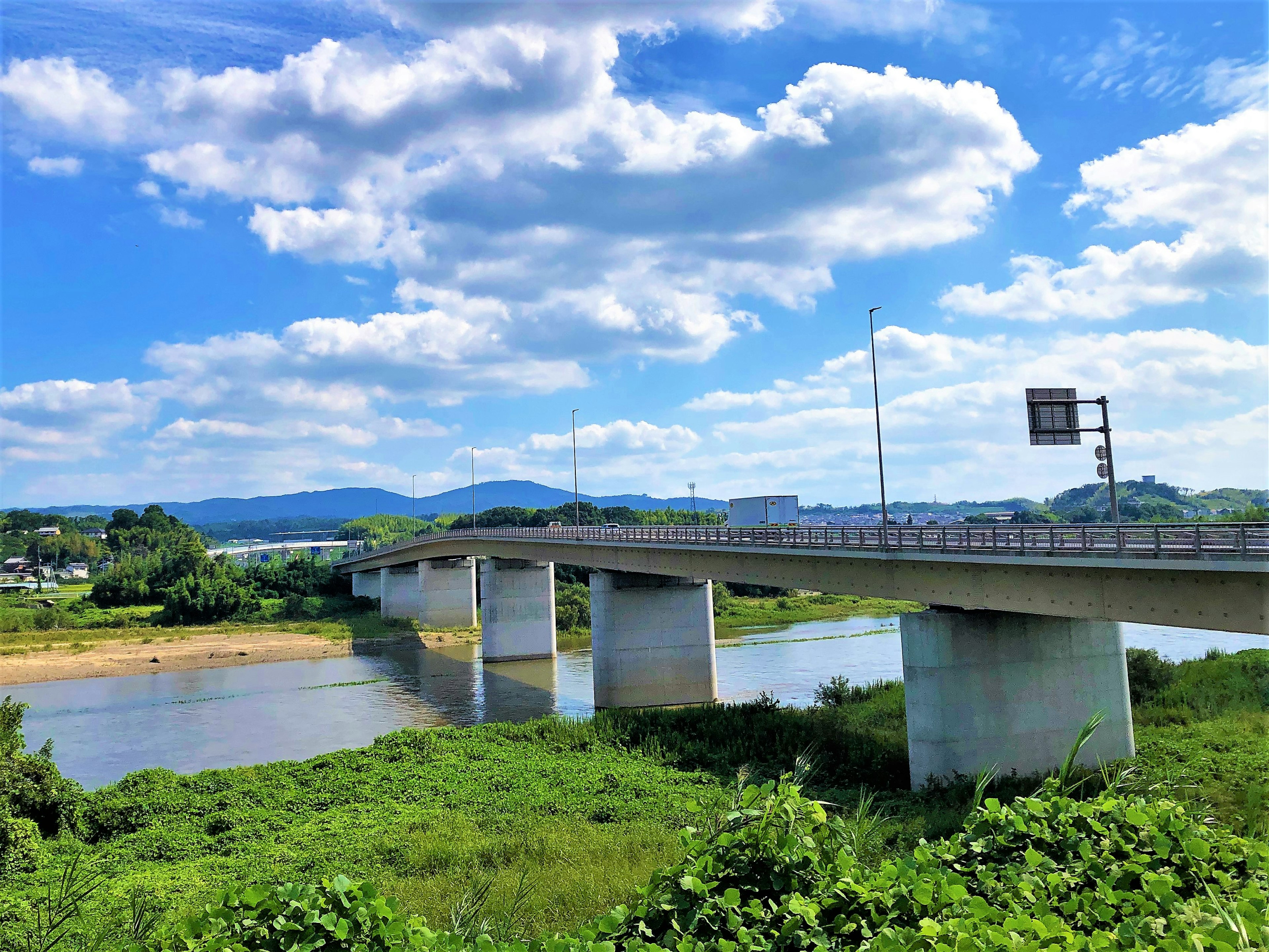 Bridge over a river with lush greenery and a blue sky