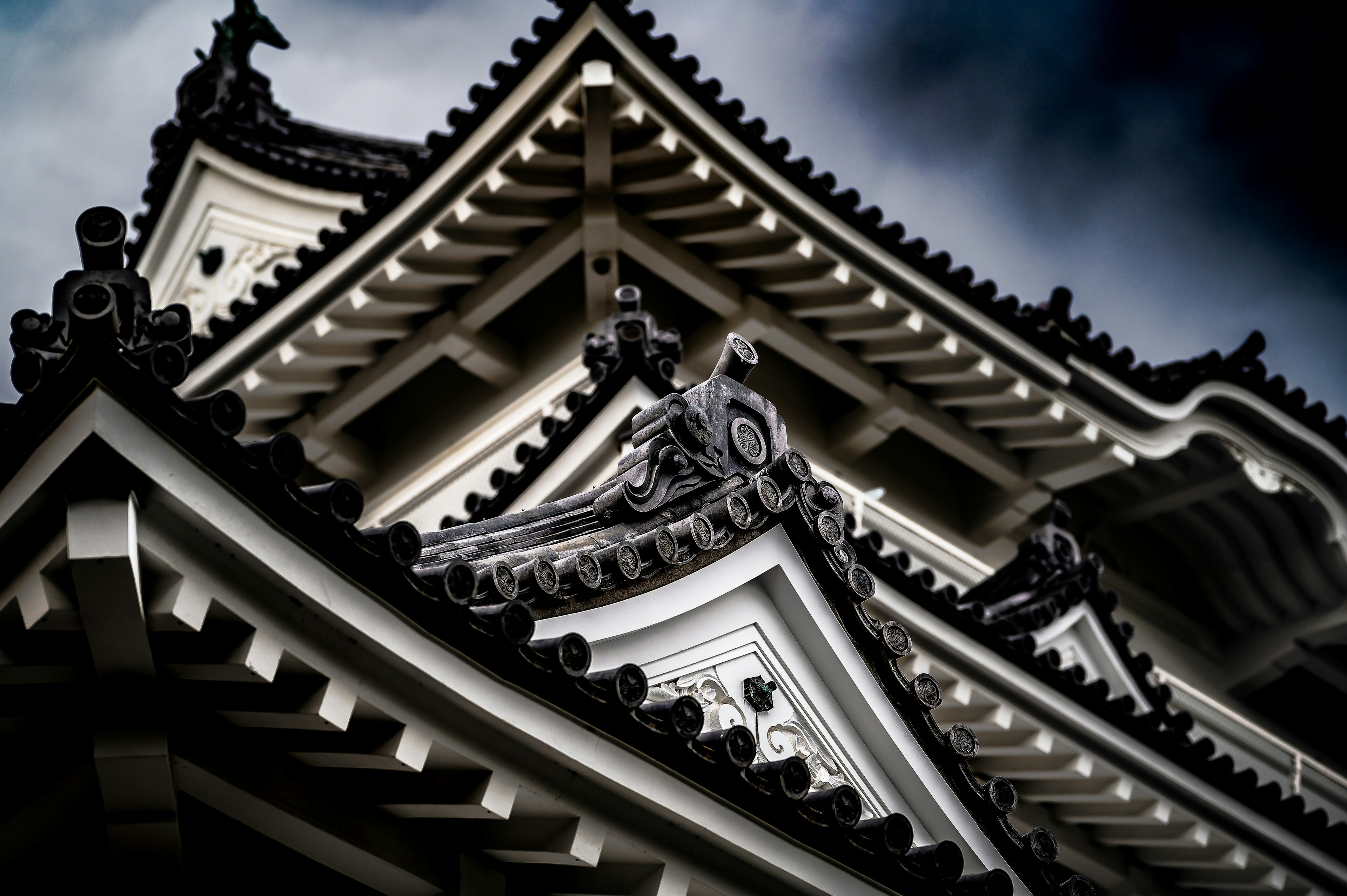 Vista detallada del techo de un castillo japonés tradicional contra un cielo oscuro