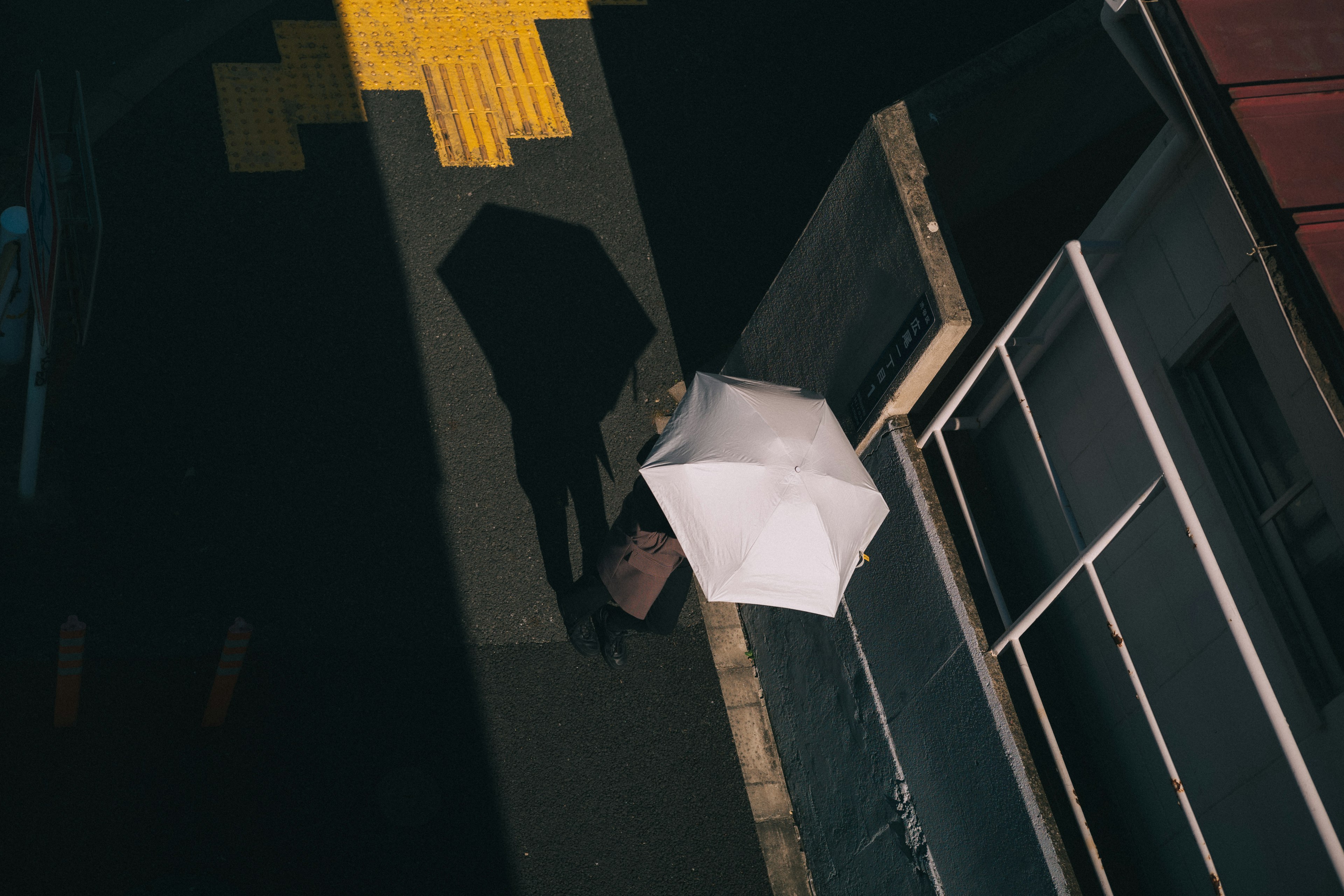 A shadow of a person holding a white umbrella in a dark street