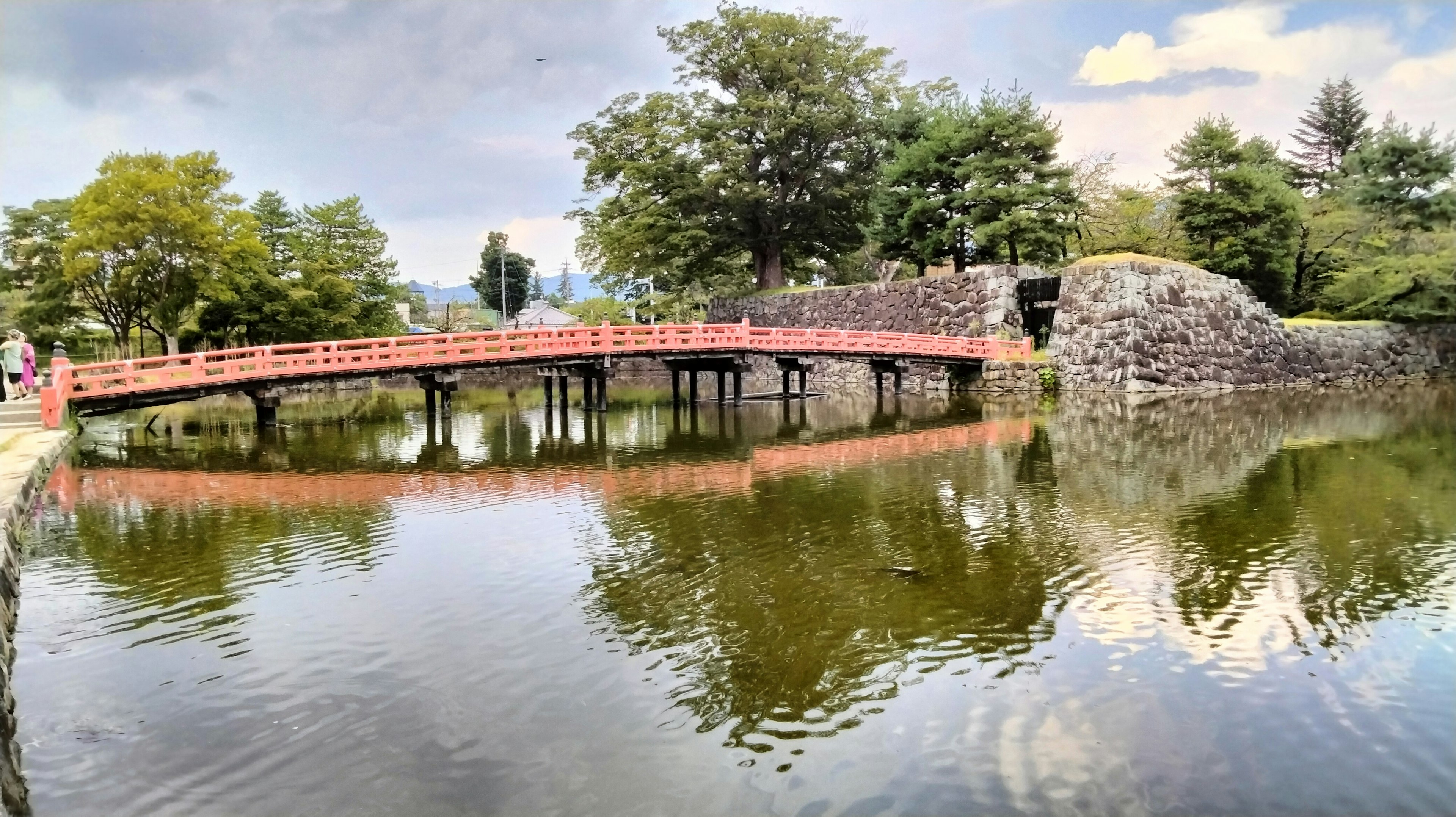 Scenic view featuring a red bridge over a serene pond