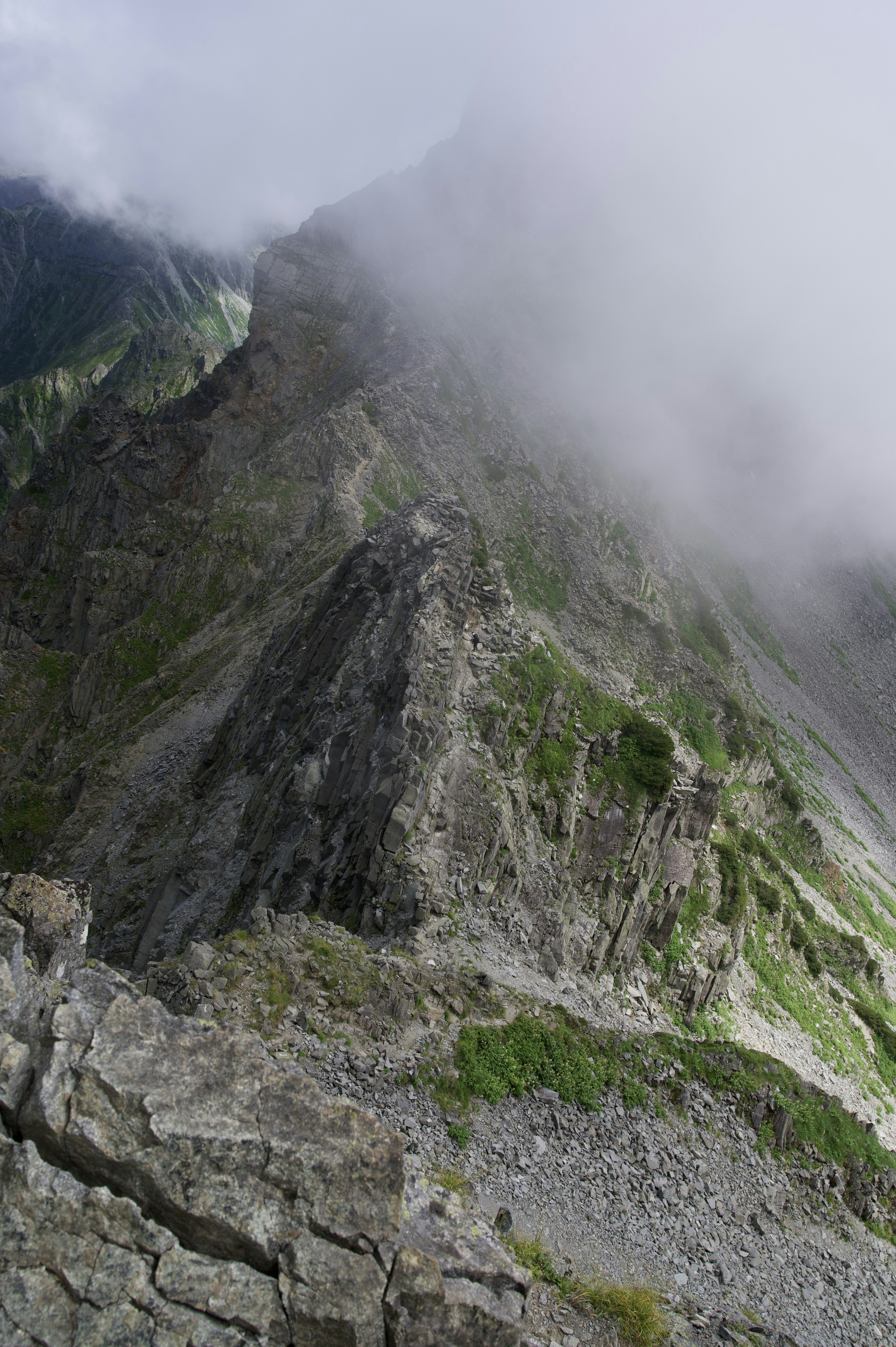 Berggipfel in Wolken gehüllt mit Gesteinsschichten