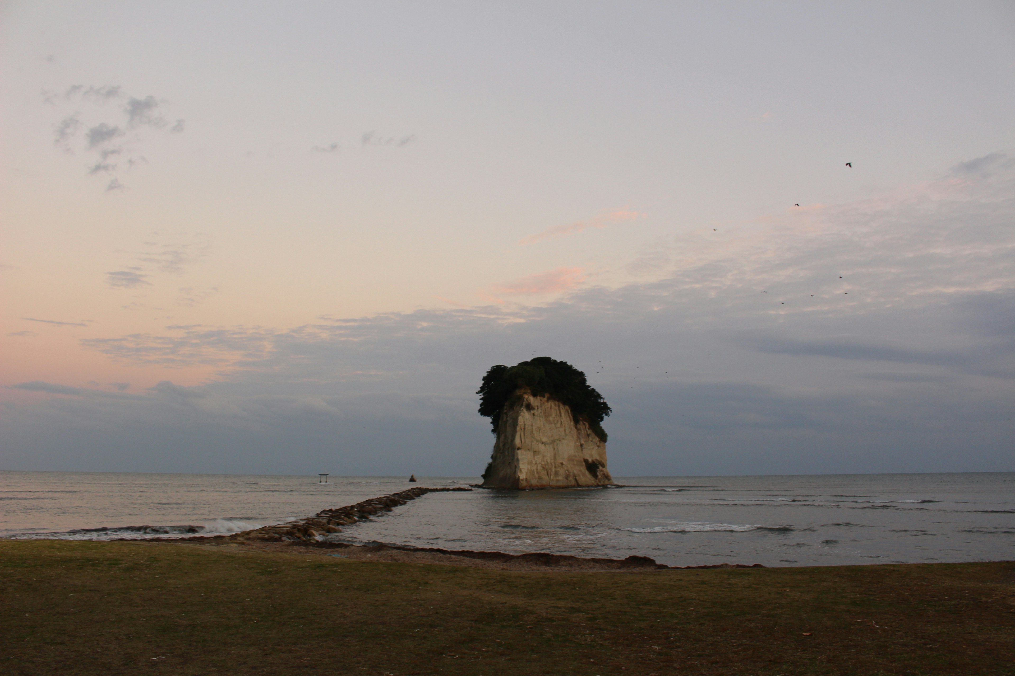 A small island in the sea with a rocky formation and calm surroundings