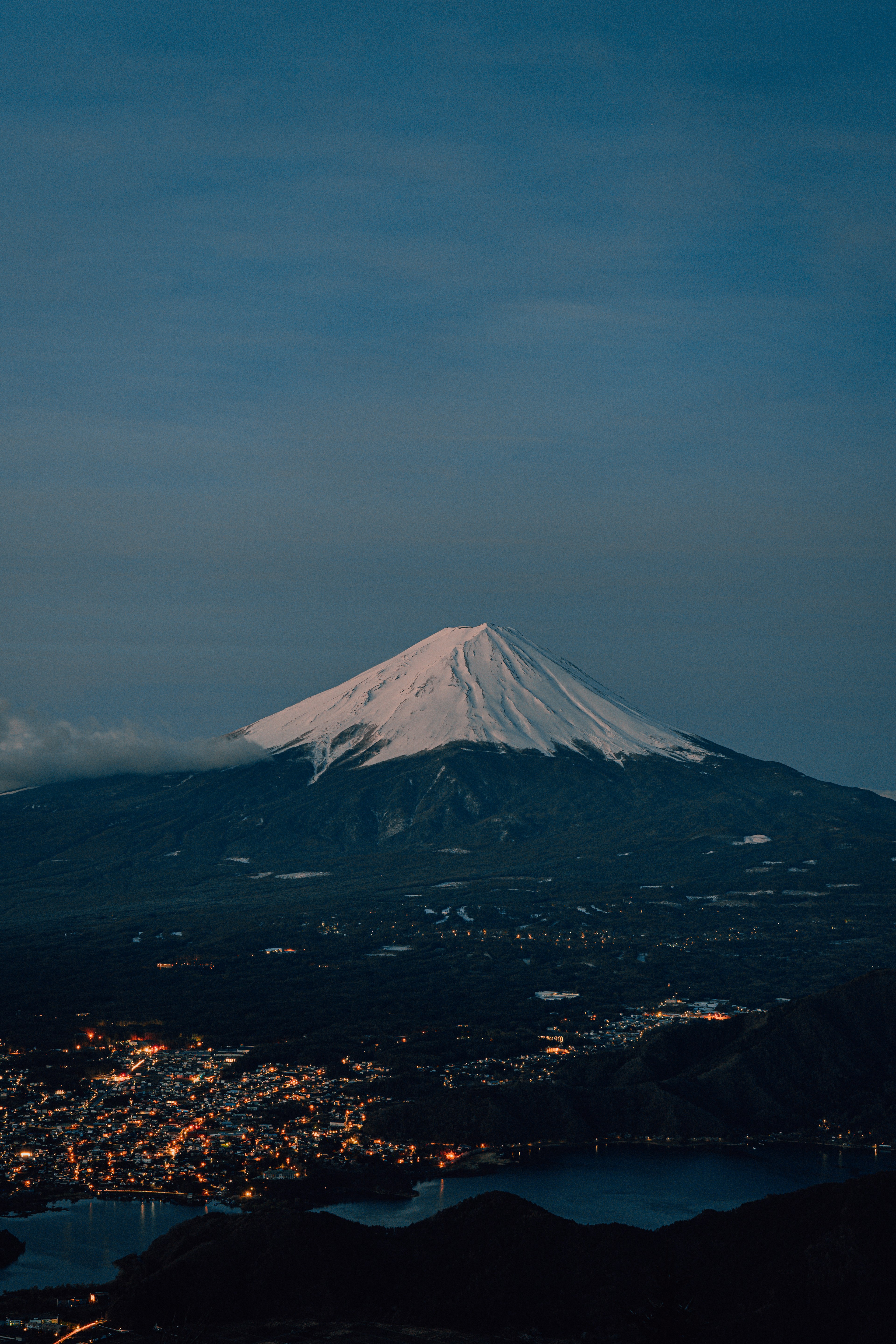 Monte Fuji con cumbre nevada y ciudad circundante de noche