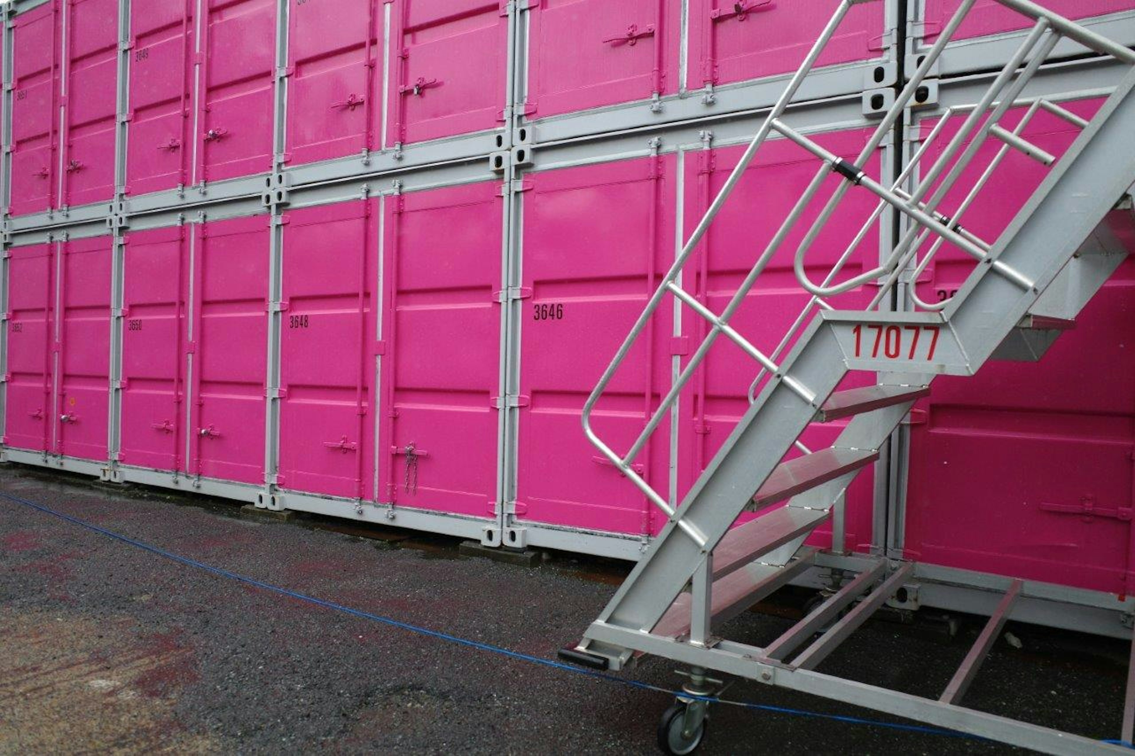 Escalier en métal à côté de conteneurs expédiés roses vifs