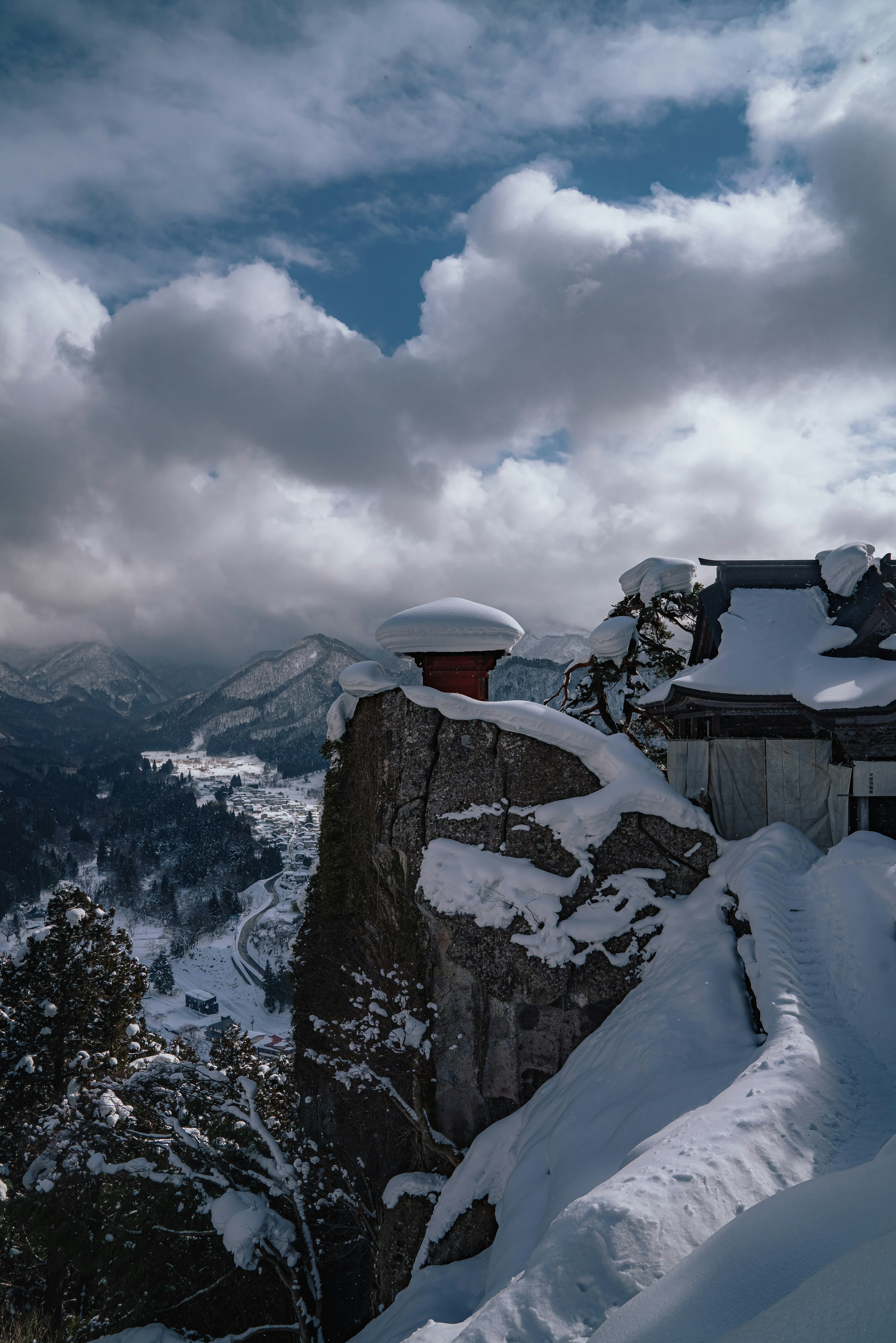 Paisaje rocoso cubierto de nieve con nubes y cielo azul