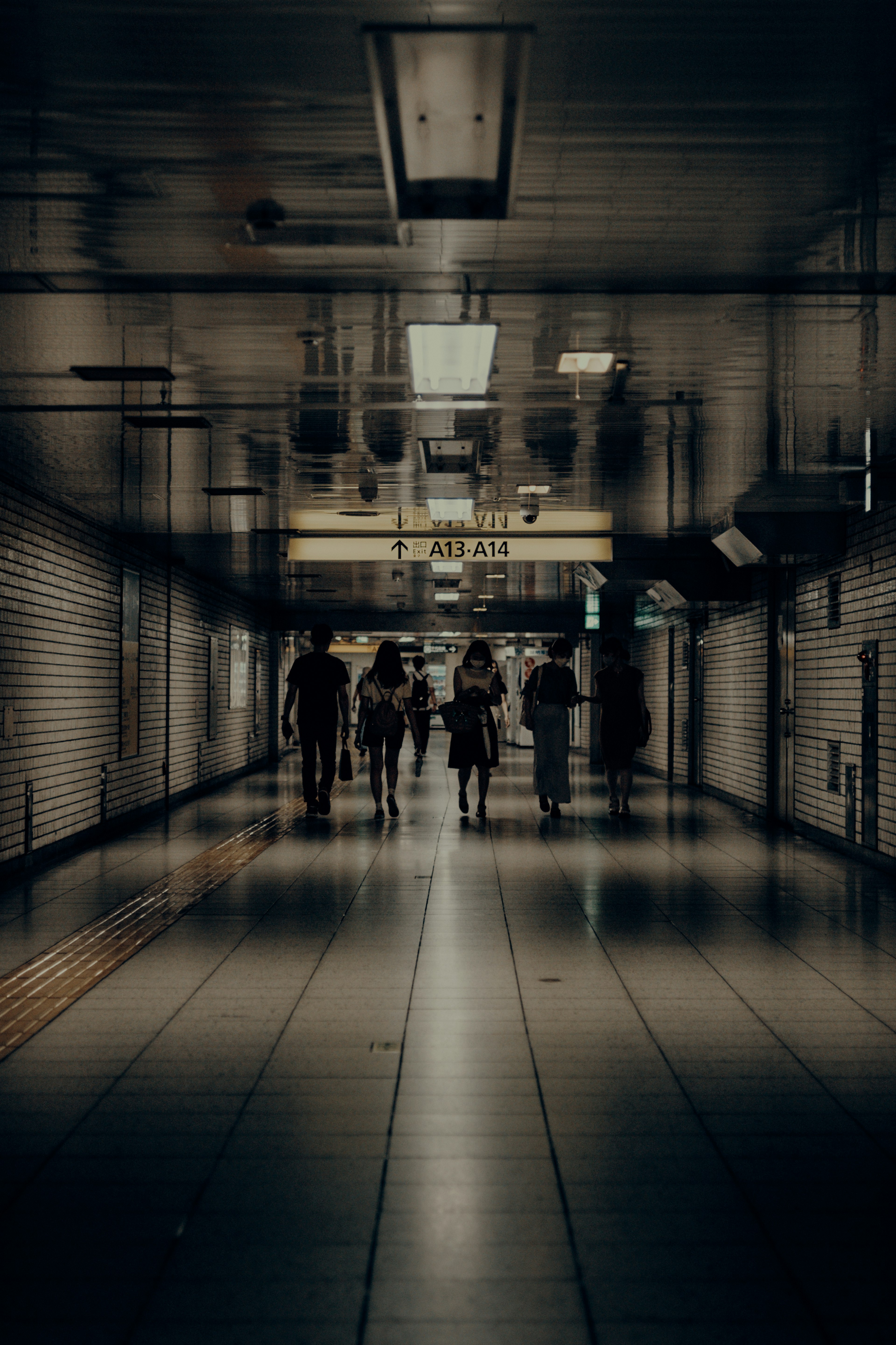 暗い通路を歩く人々のシルエットが映る画像