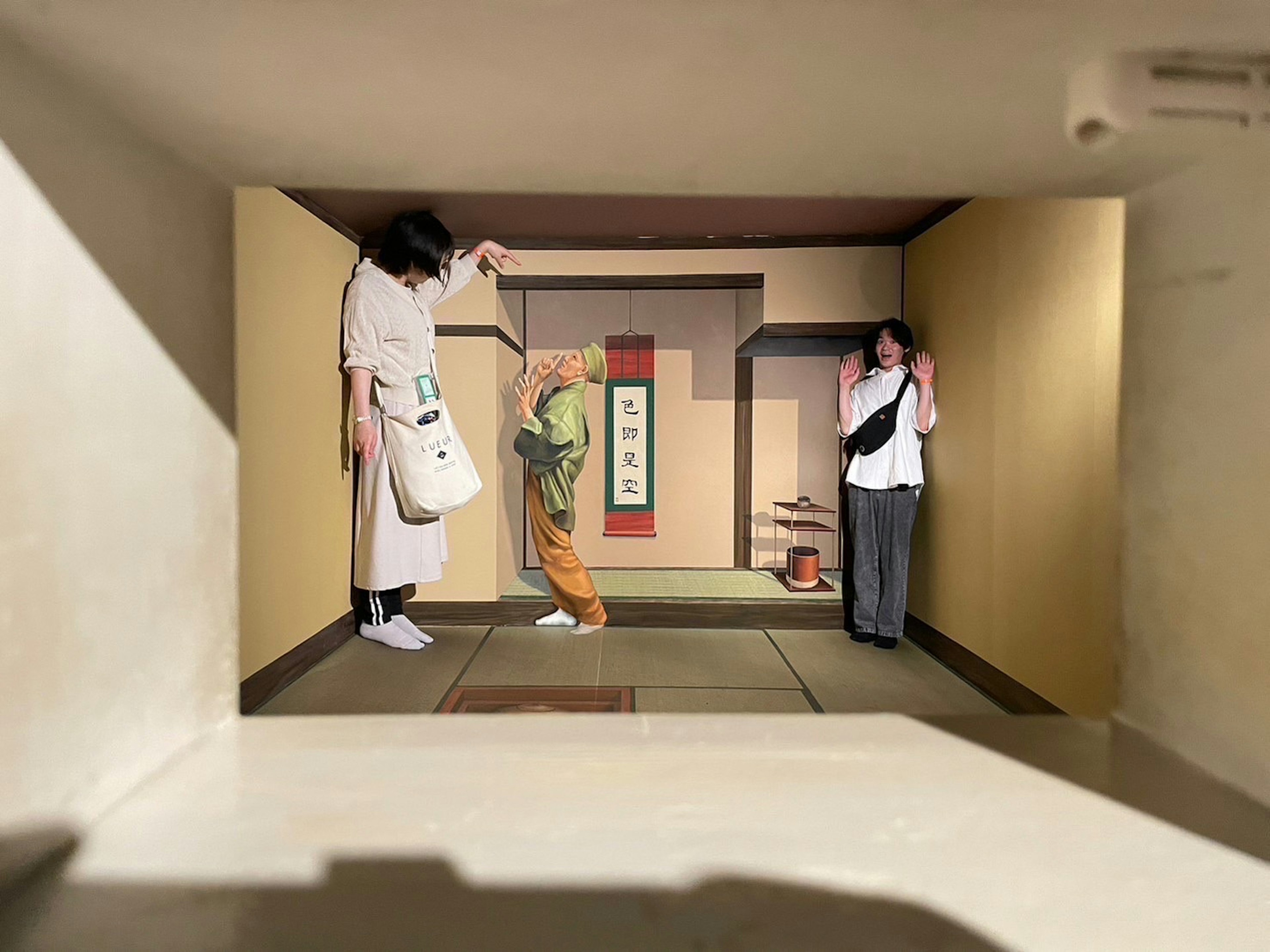 Three people in a traditional Japanese room with tatami mats and sliding doors featuring a mix of casual and traditional clothing