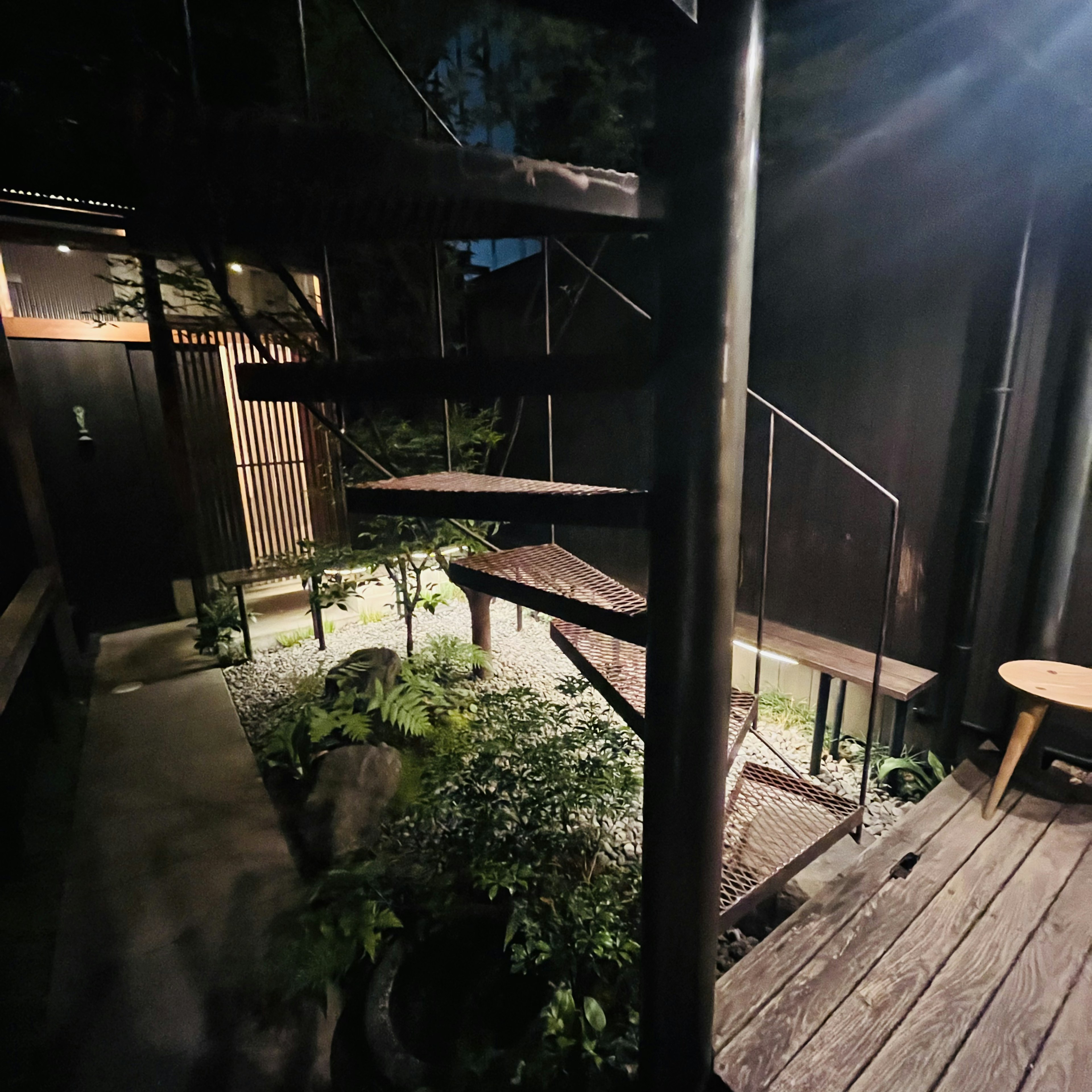 Vista nocturna de una escalera de caracol y jardín