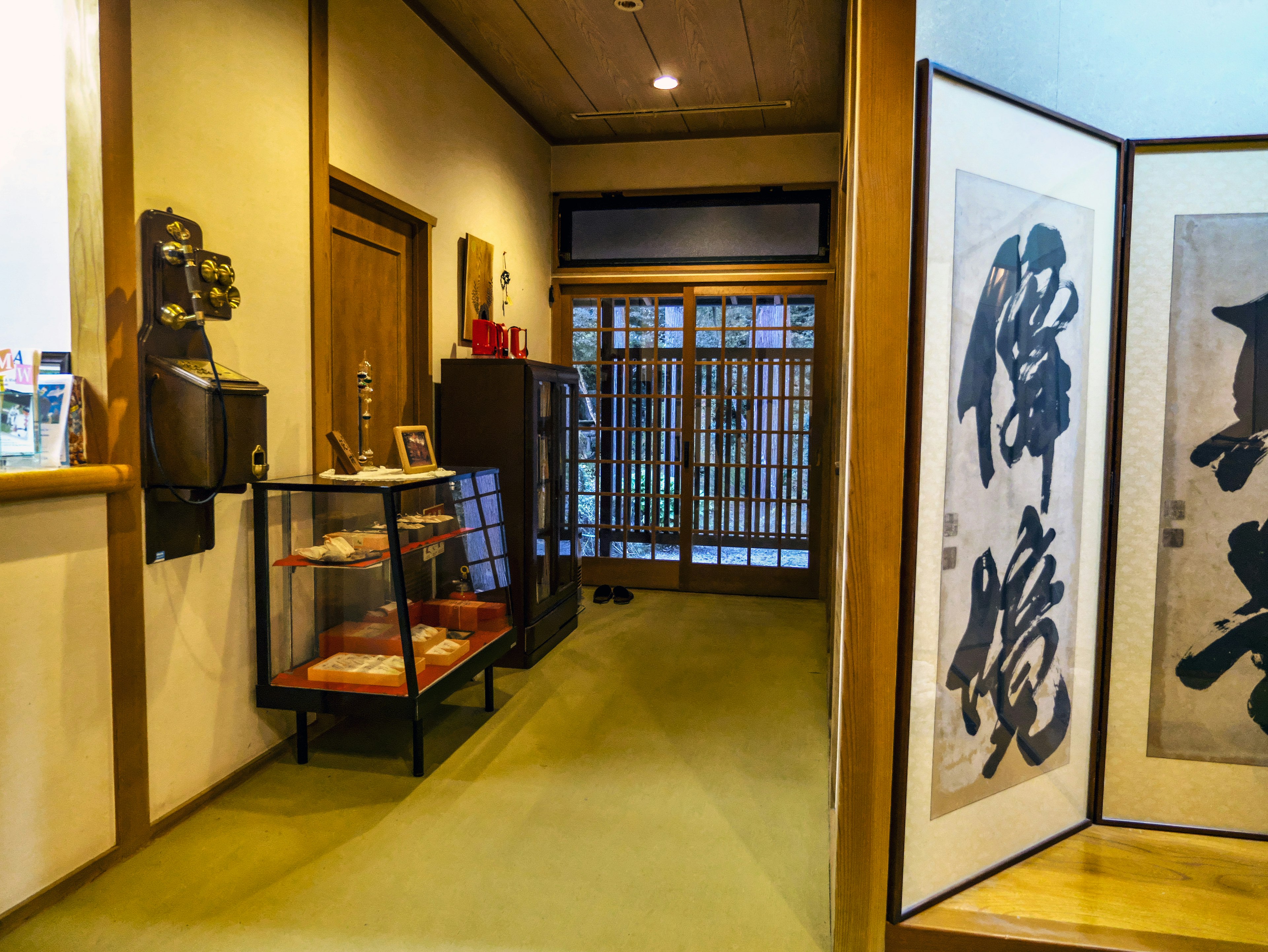 Couloir traditionnel japonais avec des portes en bois et des portes coulissantes, pièce avec des écrans shoji, œuvre de calligraphie au mur