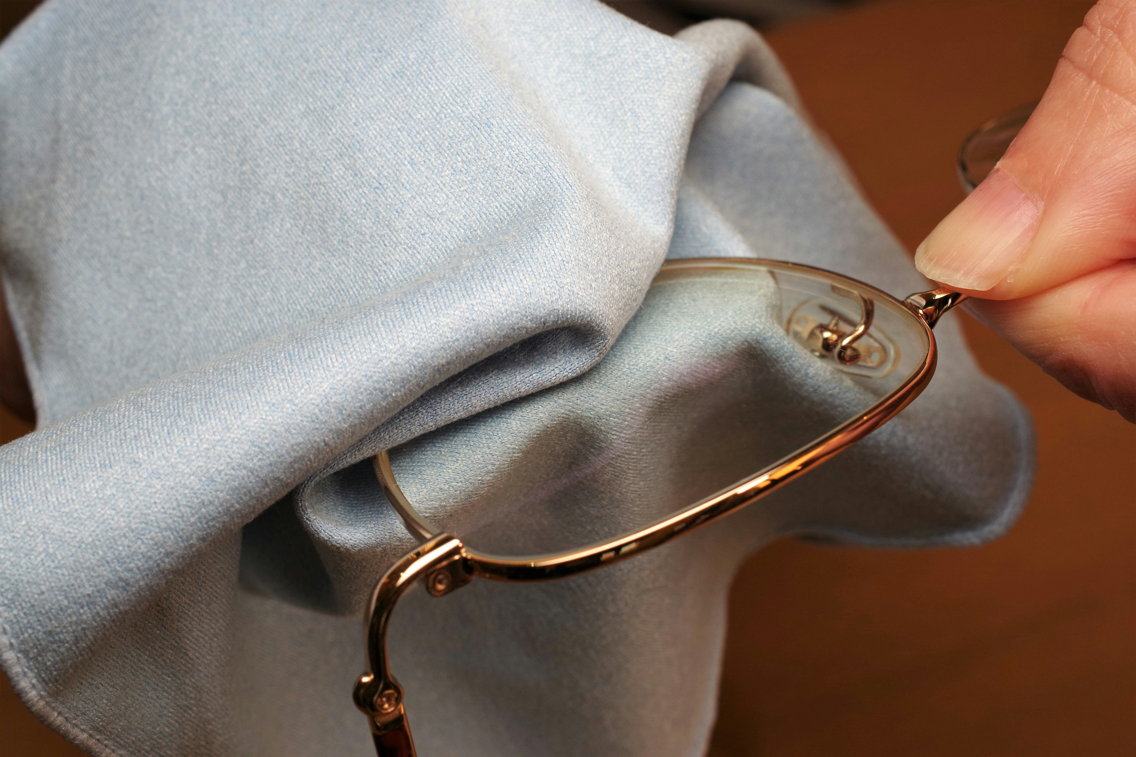 Close-up of a hand cleaning glasses with a soft cloth