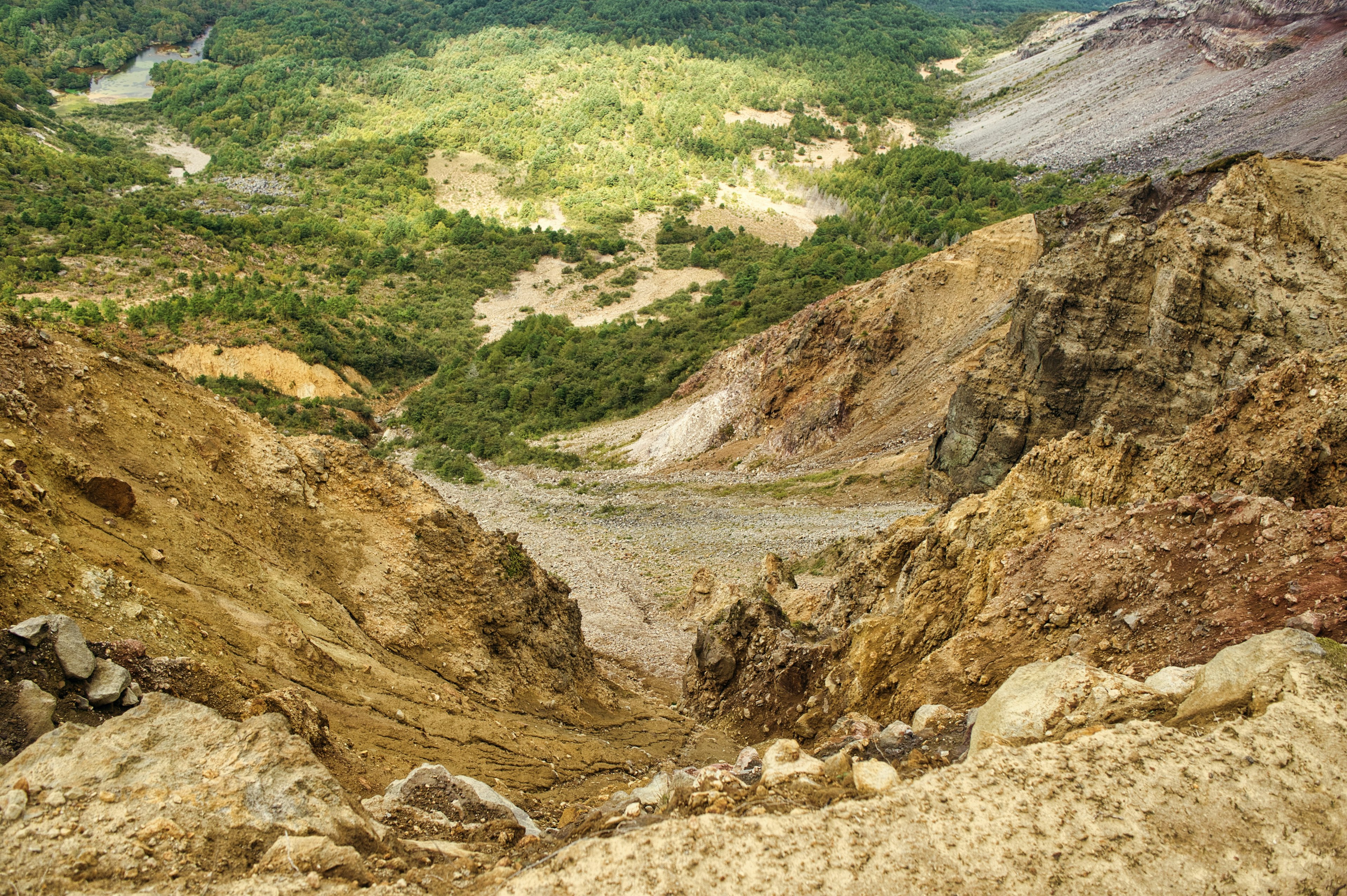 Vista desde una ladera de montaña que muestra un valle verde y un terreno rocoso