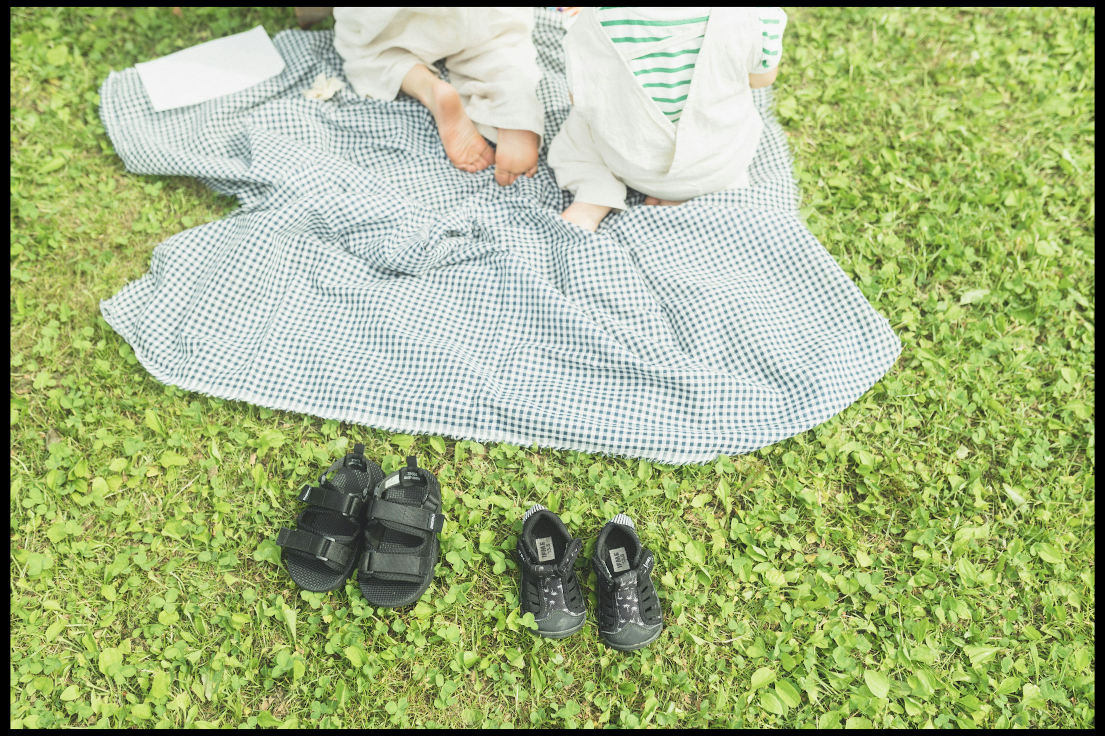 Children's feet on a checkered blanket with shoes on grass