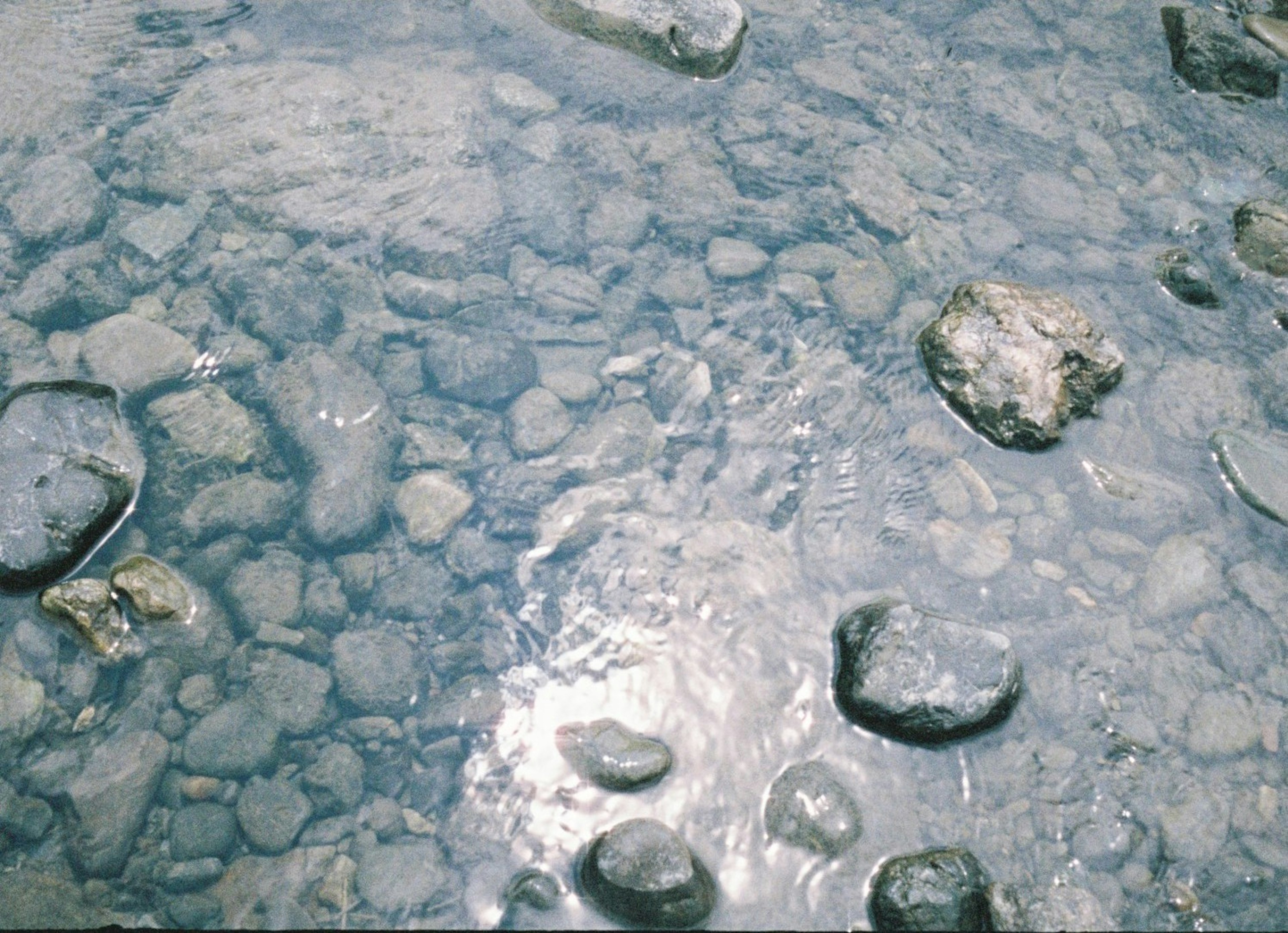 Surface of water with visible stones and reflections