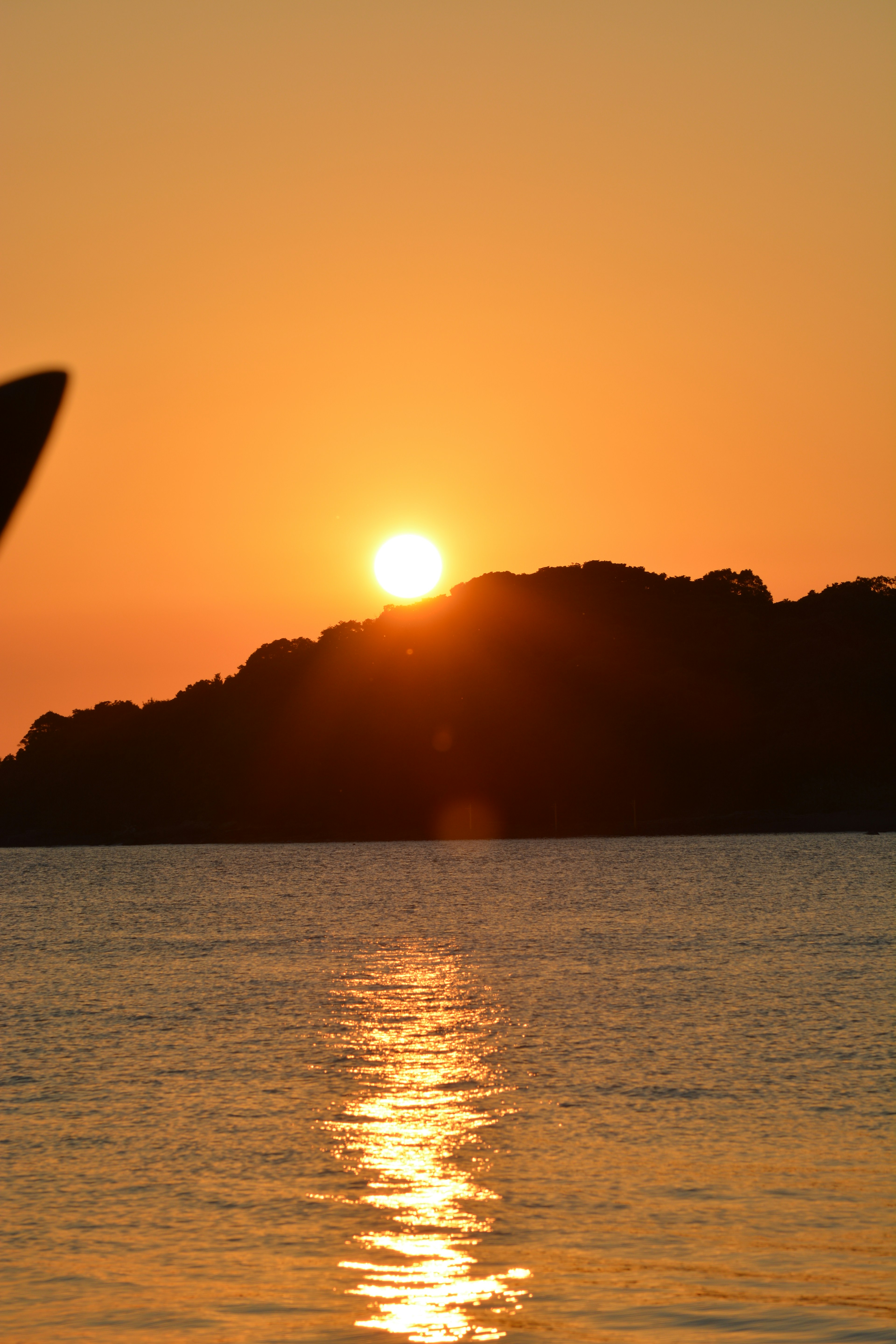 Sonnenuntergang über einem Berg mit Reflexionen im Wasser