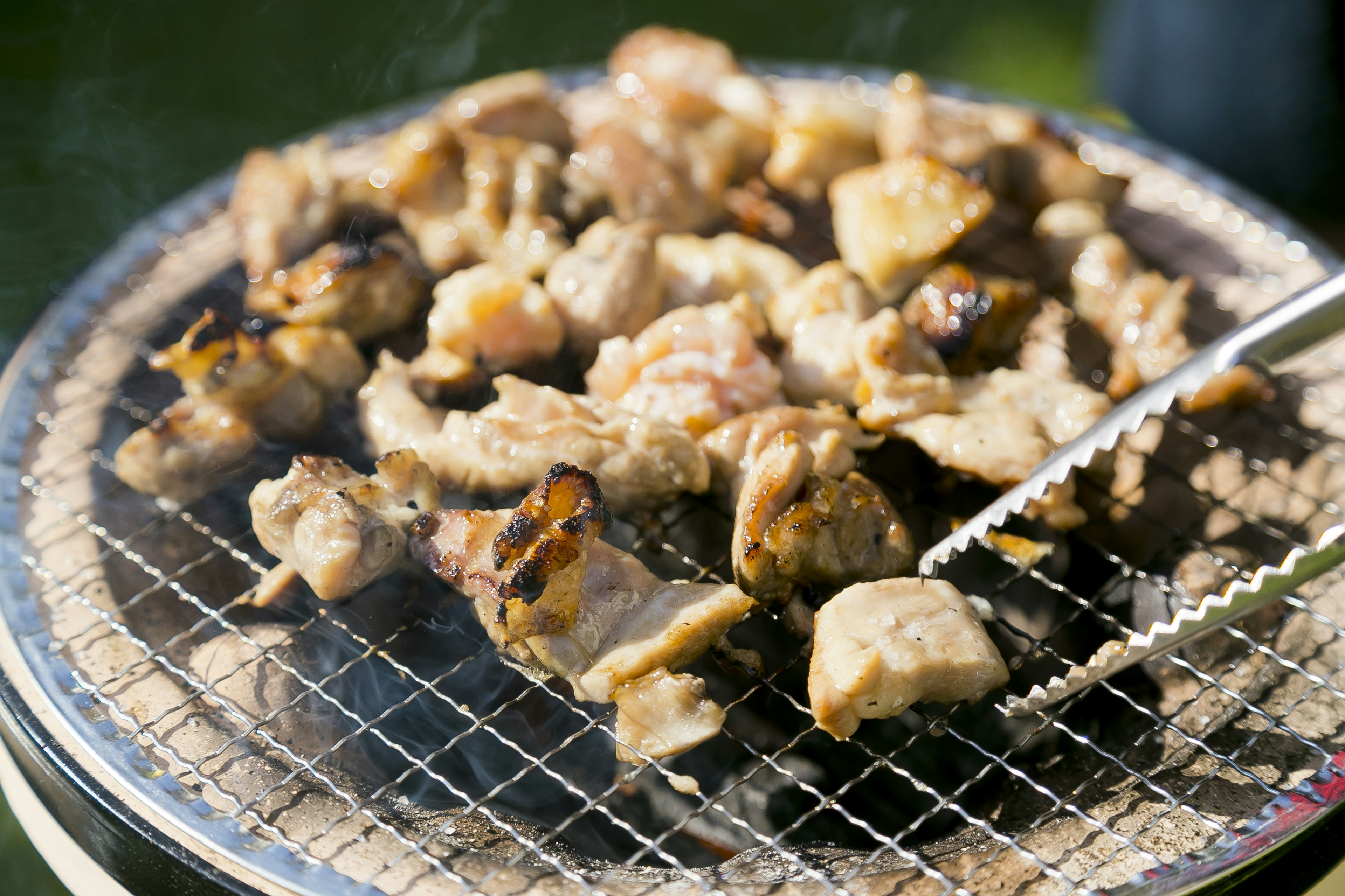 Grilled pieces of meat on a wire rack with smoke rising