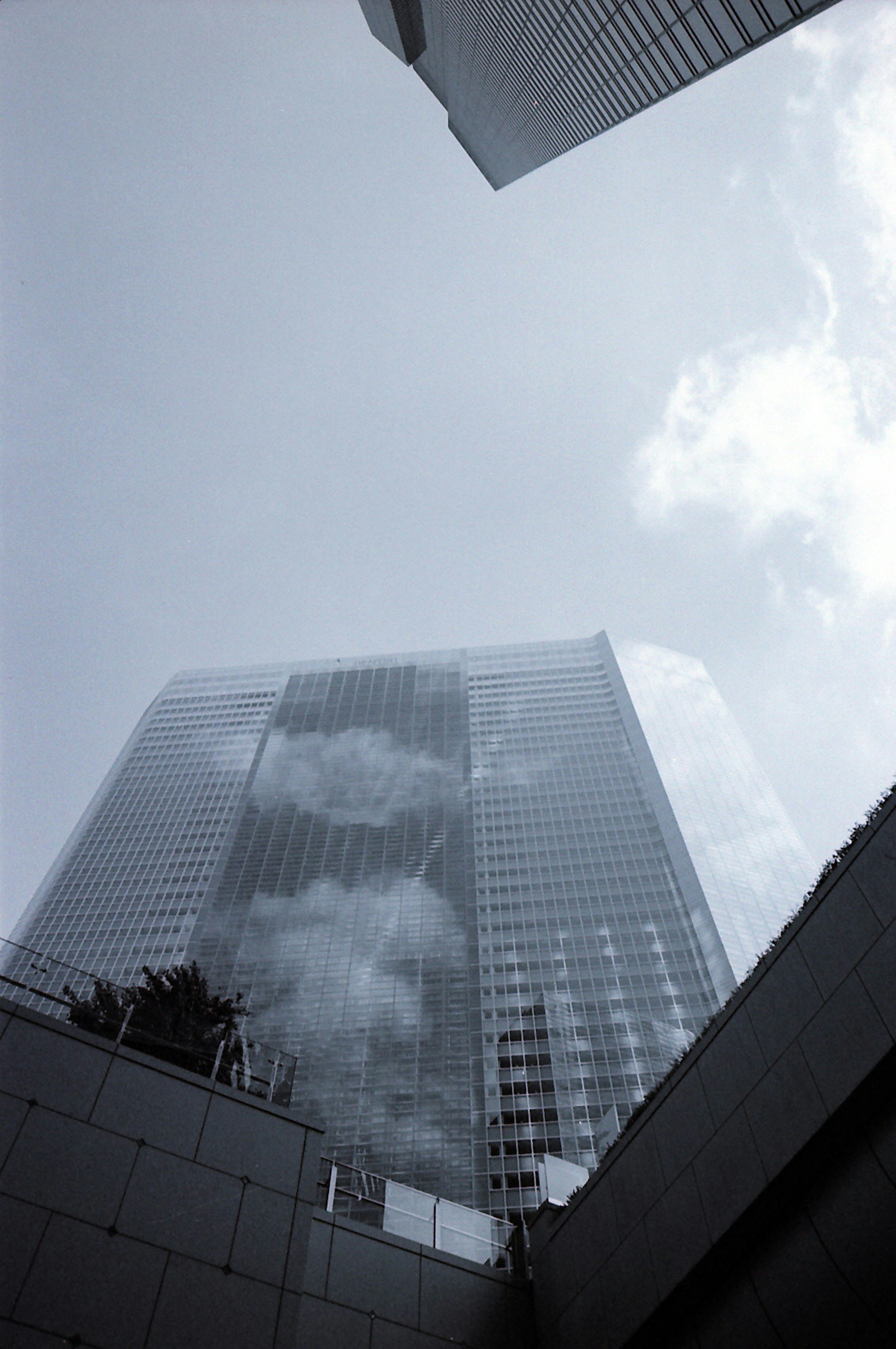 Gambar diambil dari bawah ke atas menunjukkan gedung pencakar langit dengan awan dan langit biru