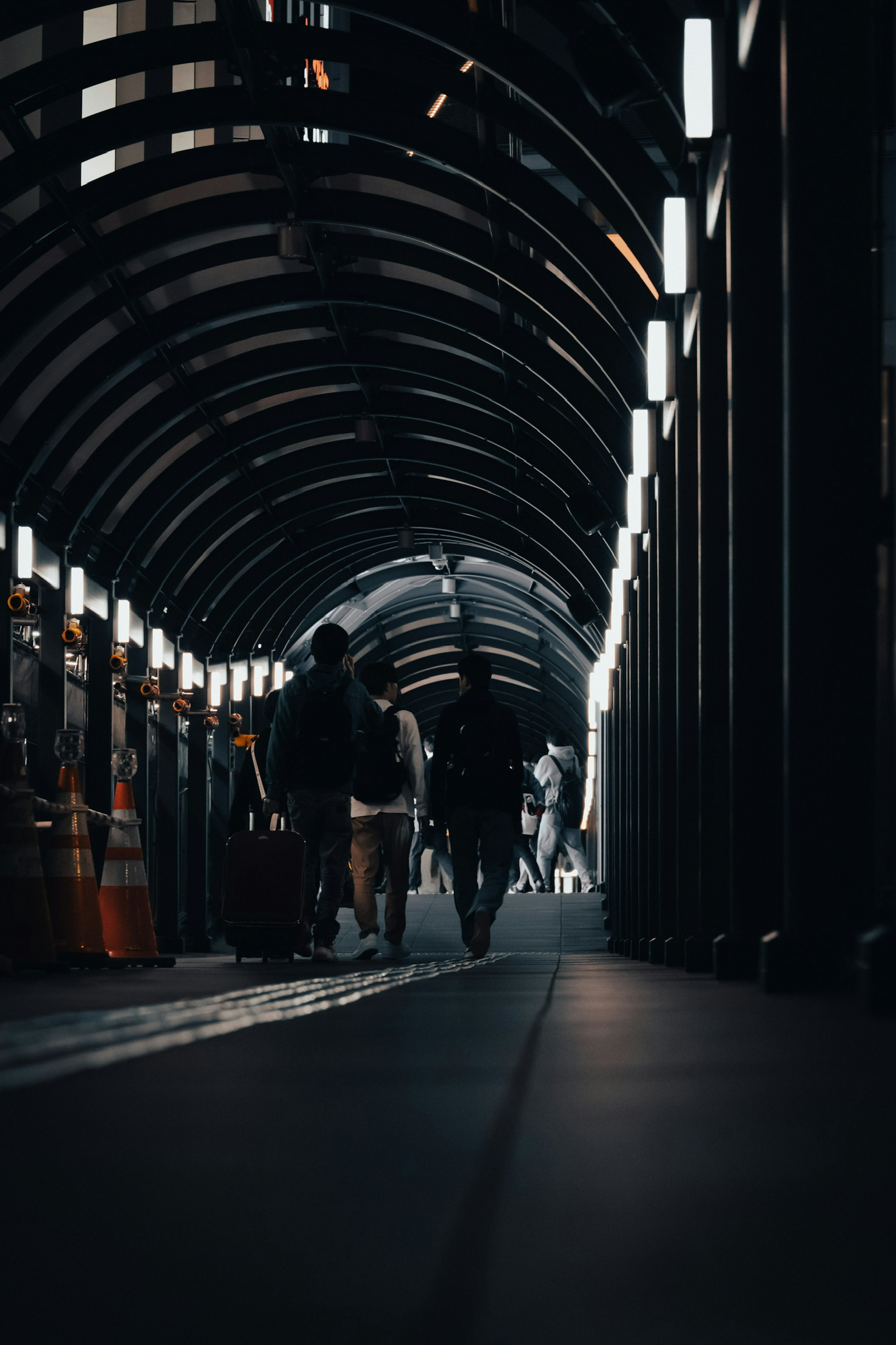 Silhouetten von Personen, die durch einen dunklen Tunnel mit Lichtern gehen