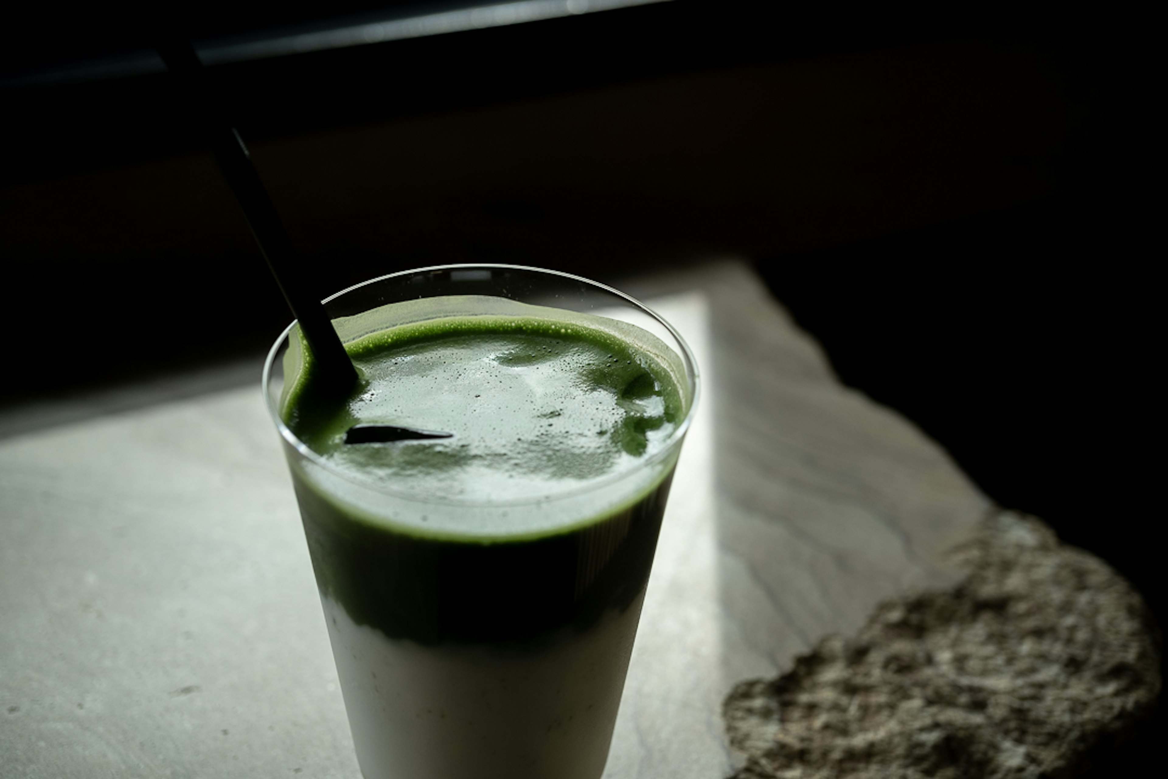 Bicchiere trasparente con bevanda verde e cannuccia nera