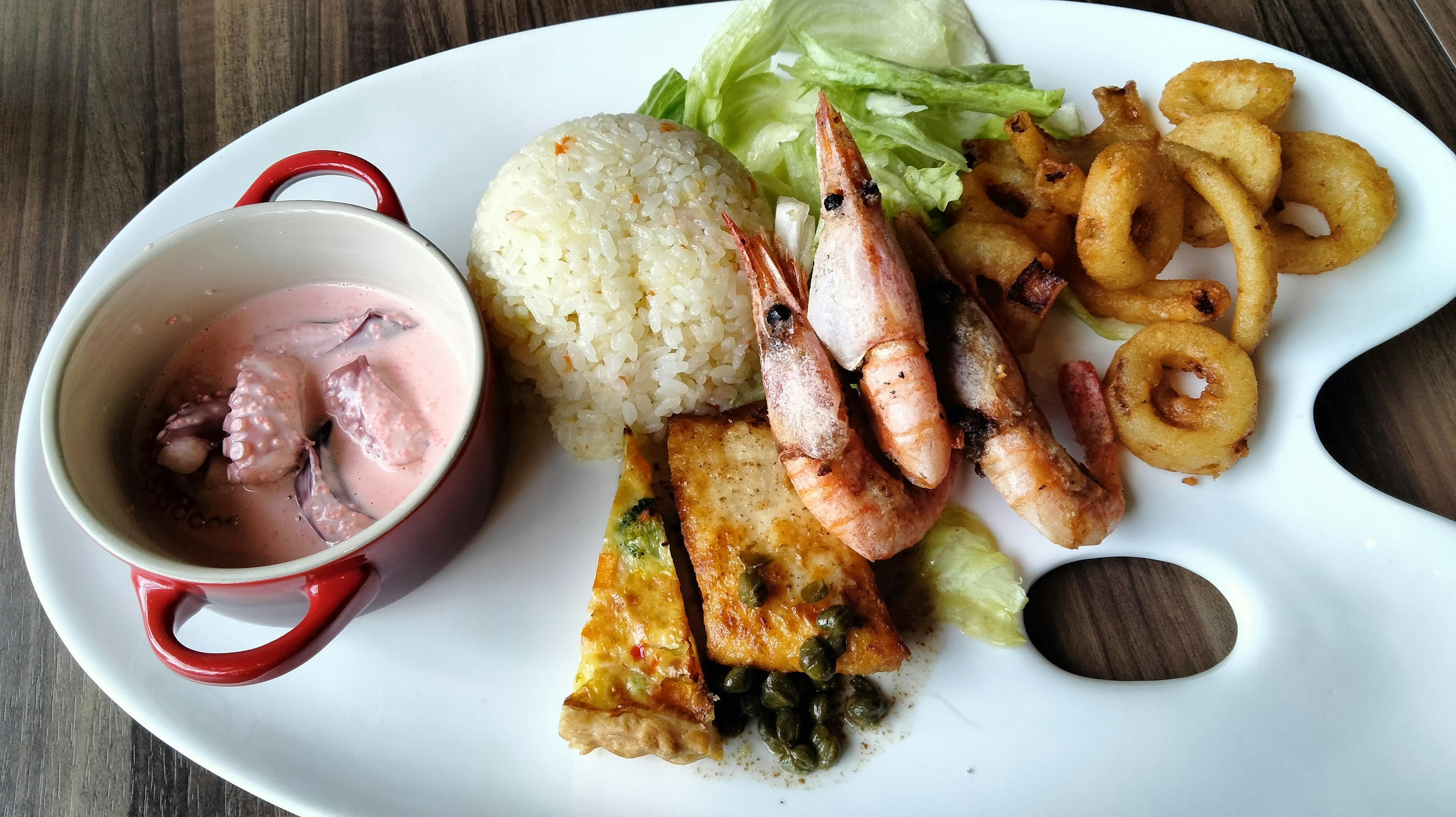 Un plato de camarones con arroz, ensalada y alimentos fritos