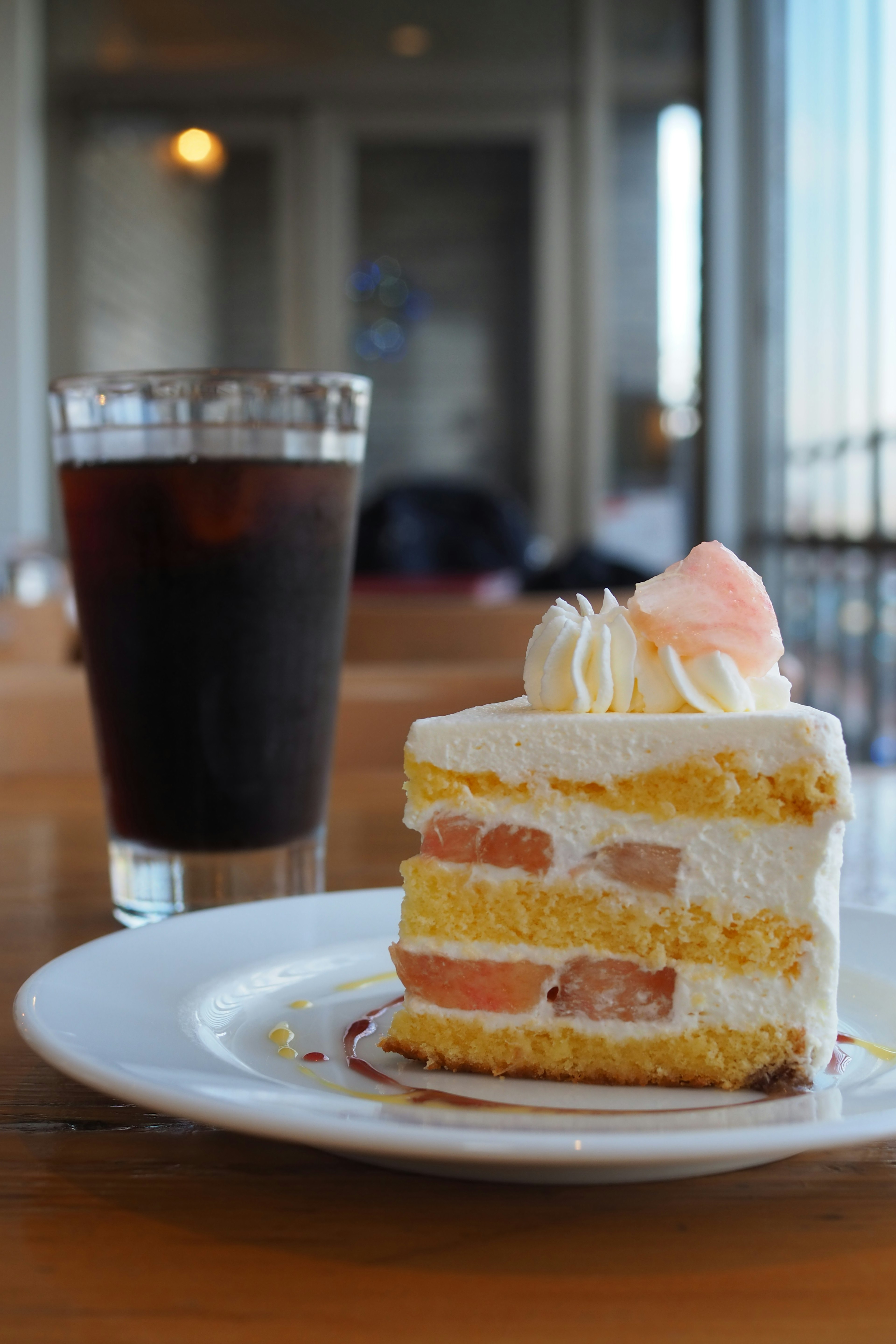 Una bella torta a strati e un bicchiere di cola su un tavolo di legno