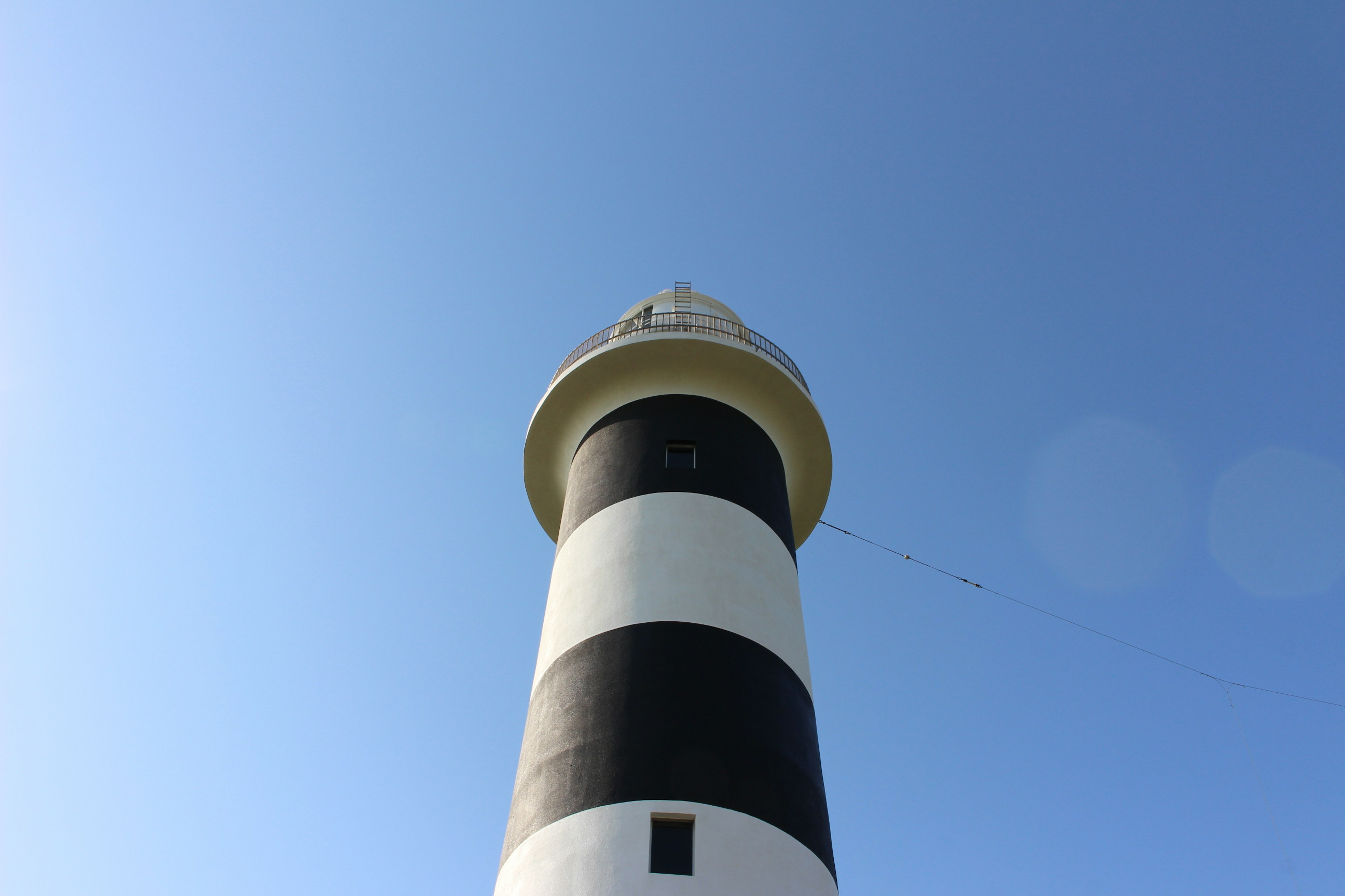 Lighthouse with black and white stripes under a clear blue sky