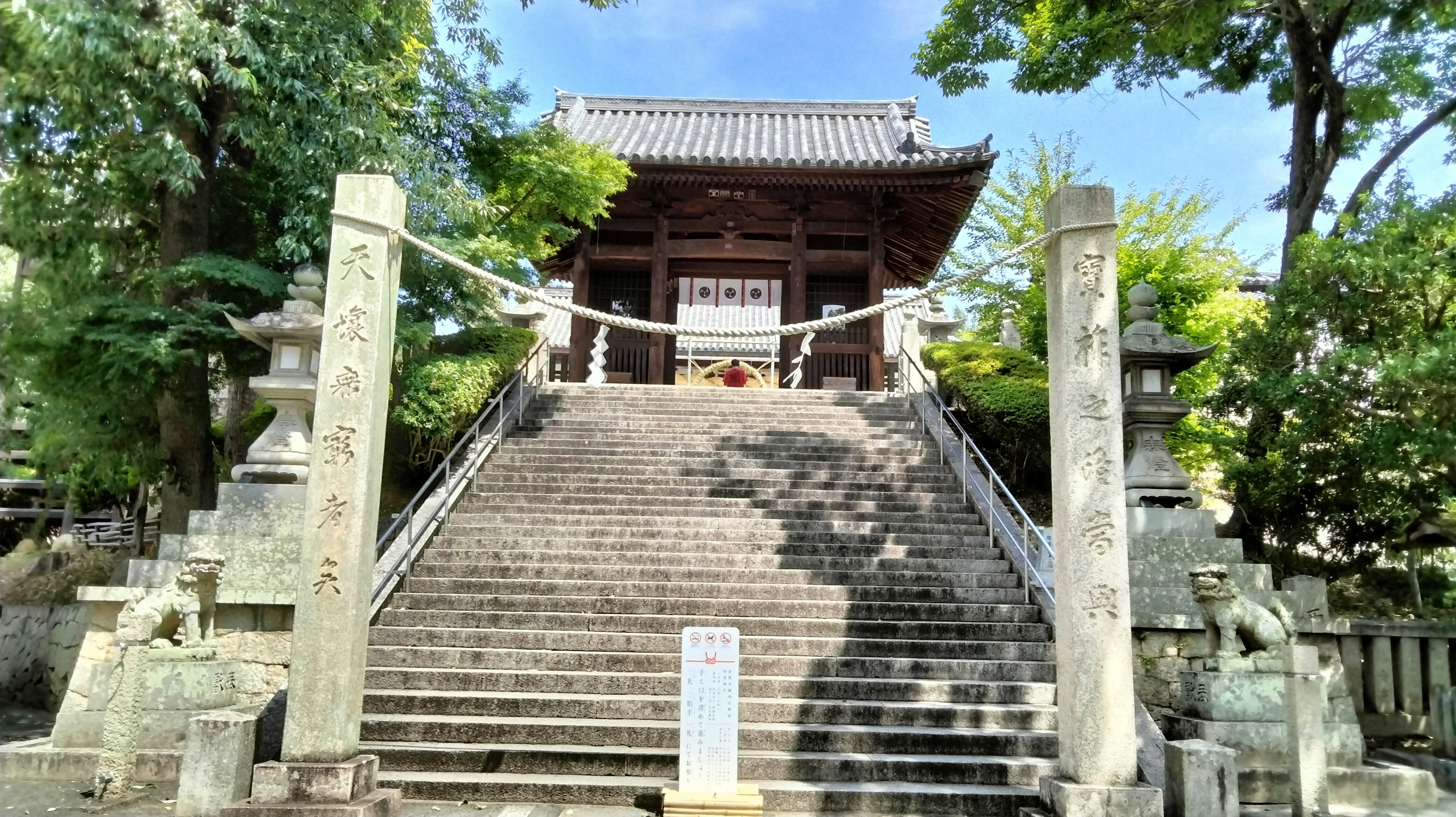 Eingang zu einem traditionellen Tempel mit Steinstufen und umliegendem Grün