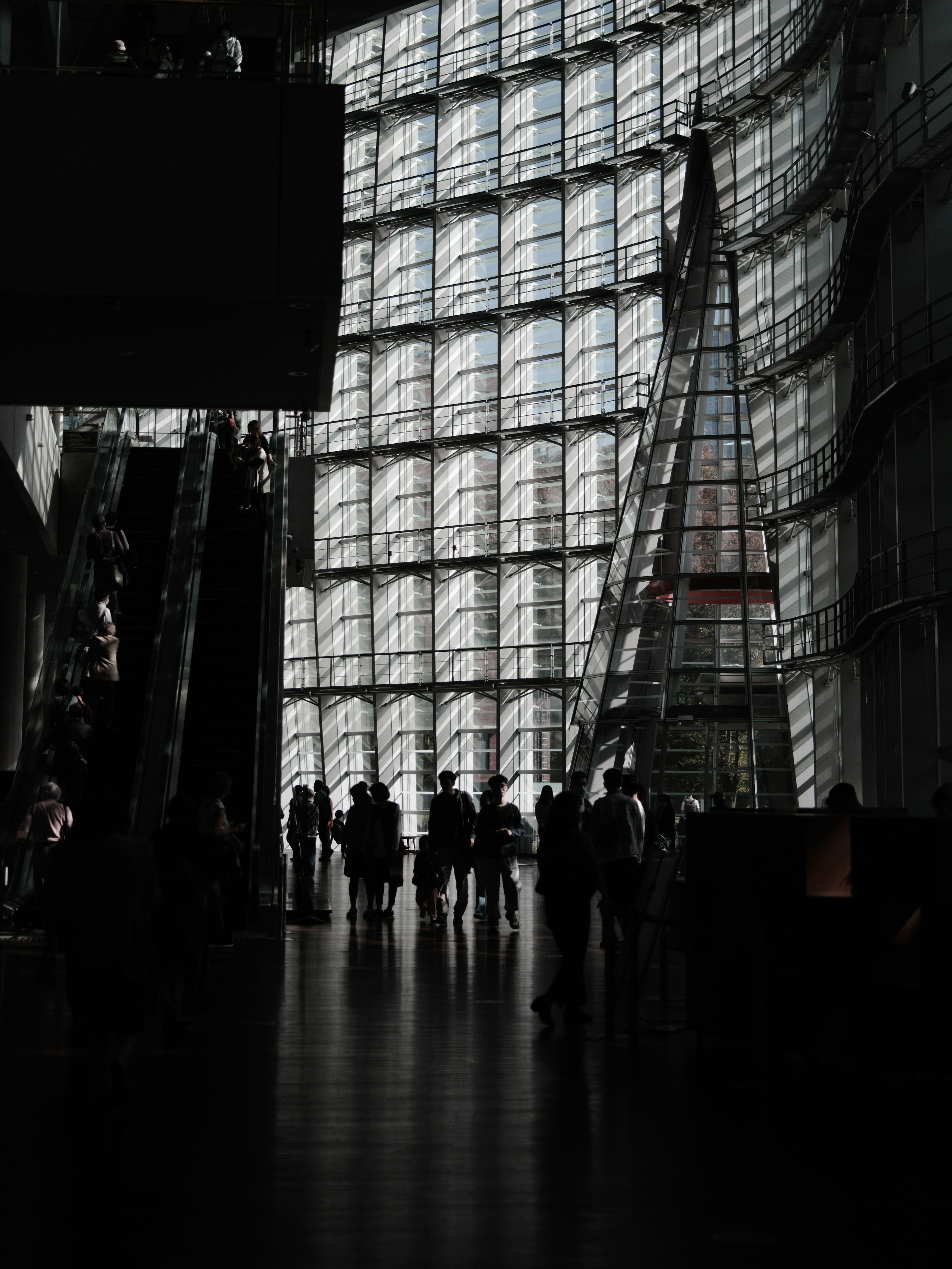 Silhouettes de personnes à l'intérieur d'un bâtiment moderne avec de grandes fenêtres en verre