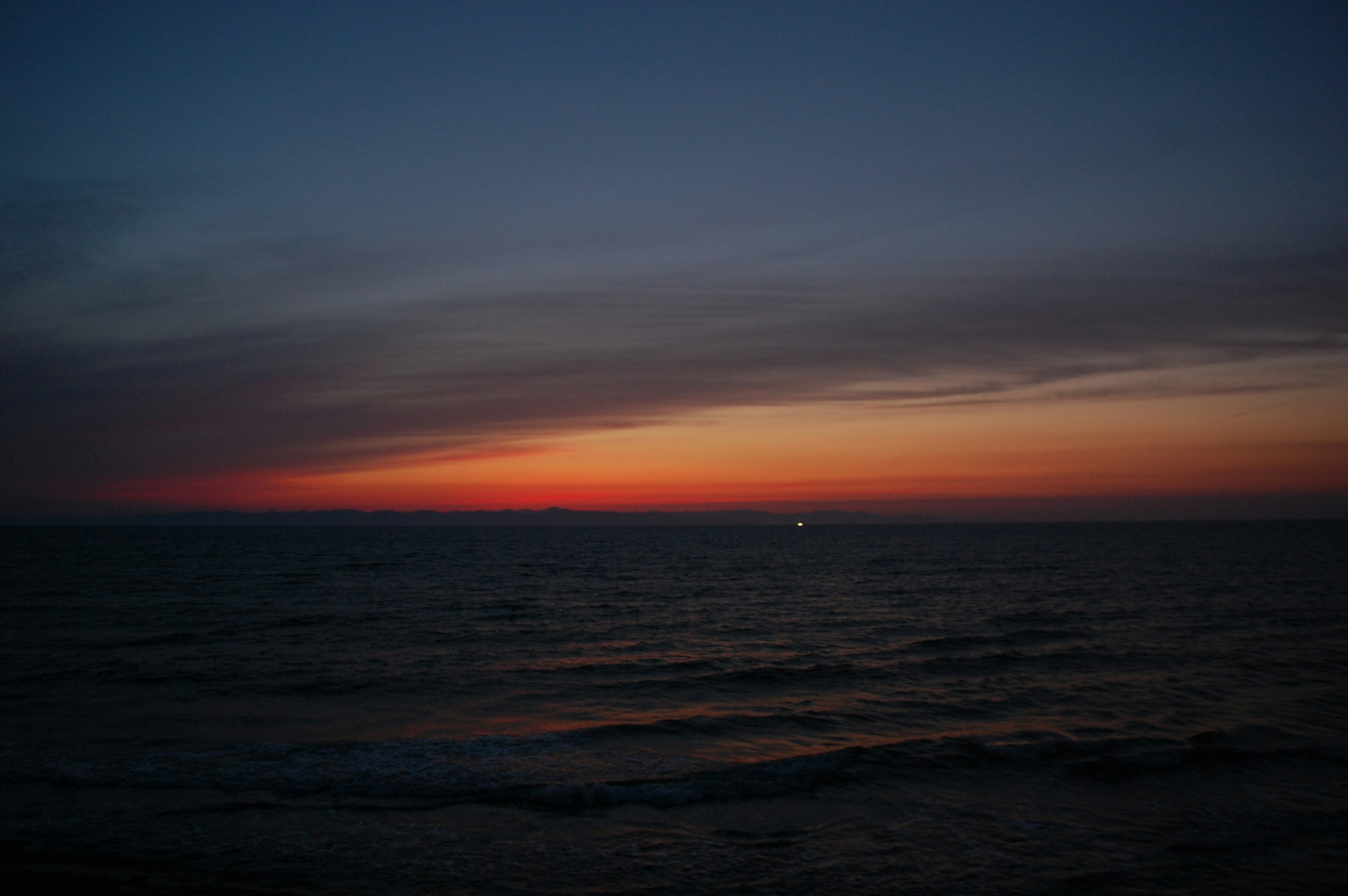 Sonnenuntergang über dem Ozean mit blauem und orangefarbenem Farbverlauf ruhige Wellen