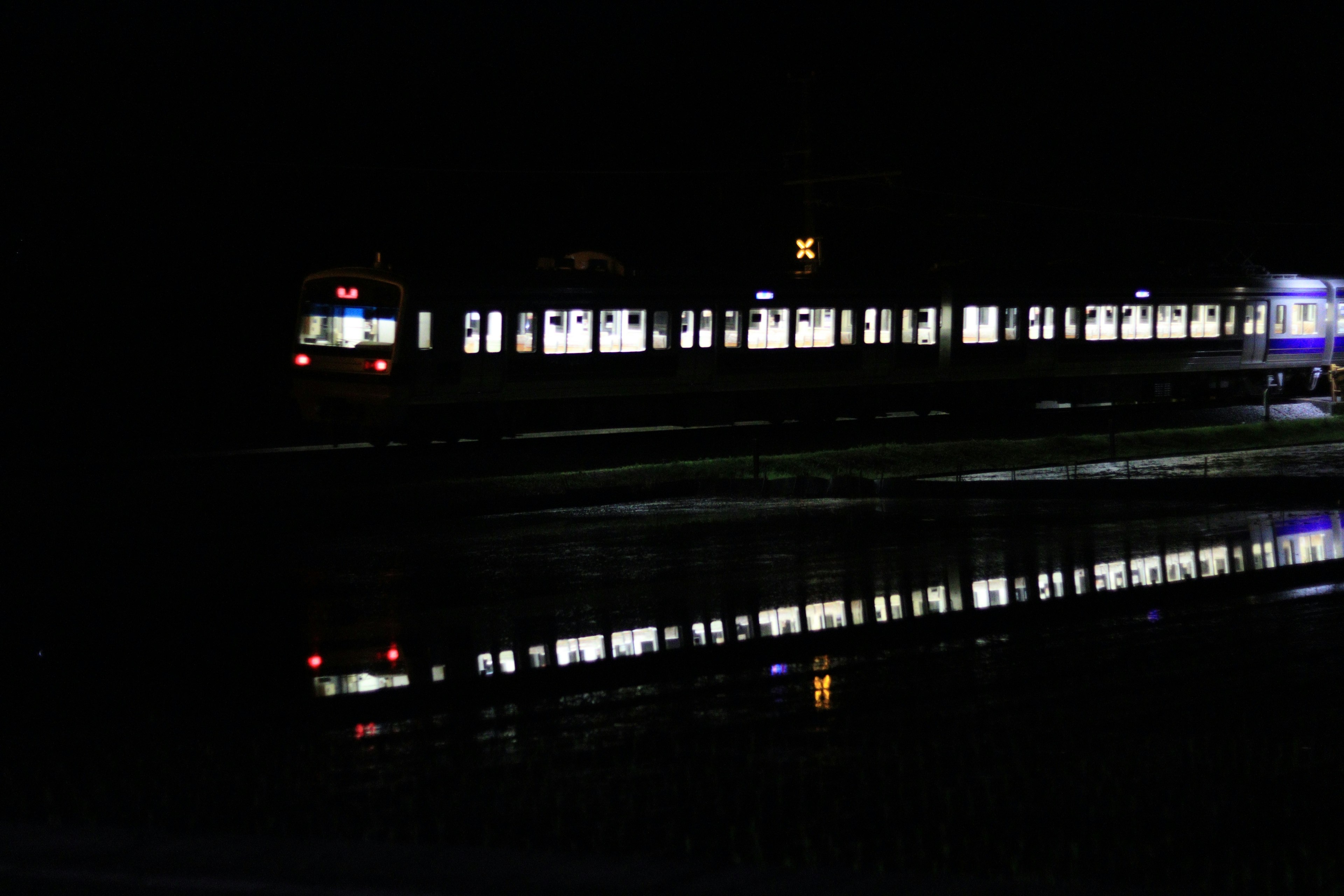 Train stopped at night with reflections in water