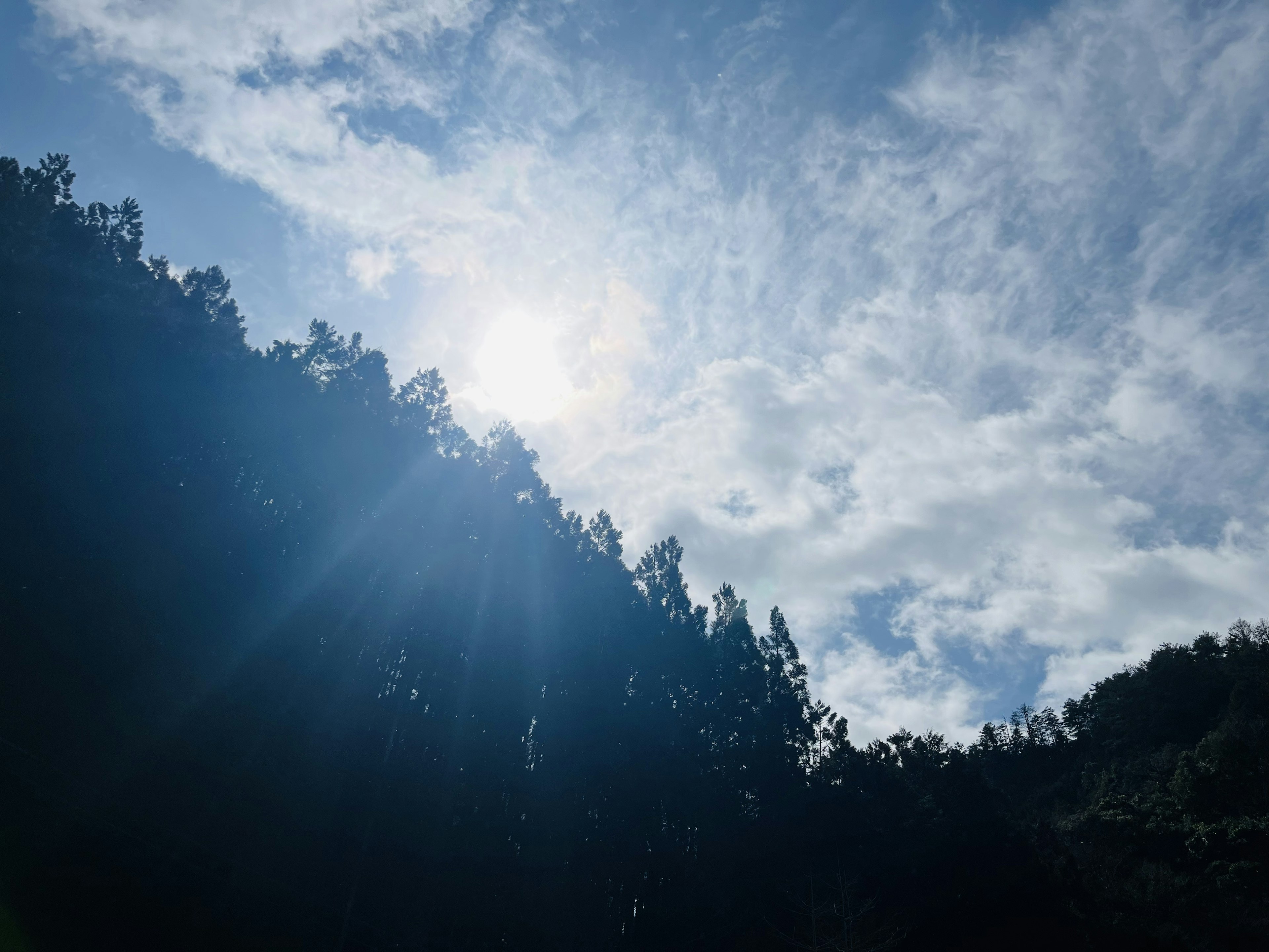 山脈的輪廓在明亮的天空下，伴隨著雲彩和陽光