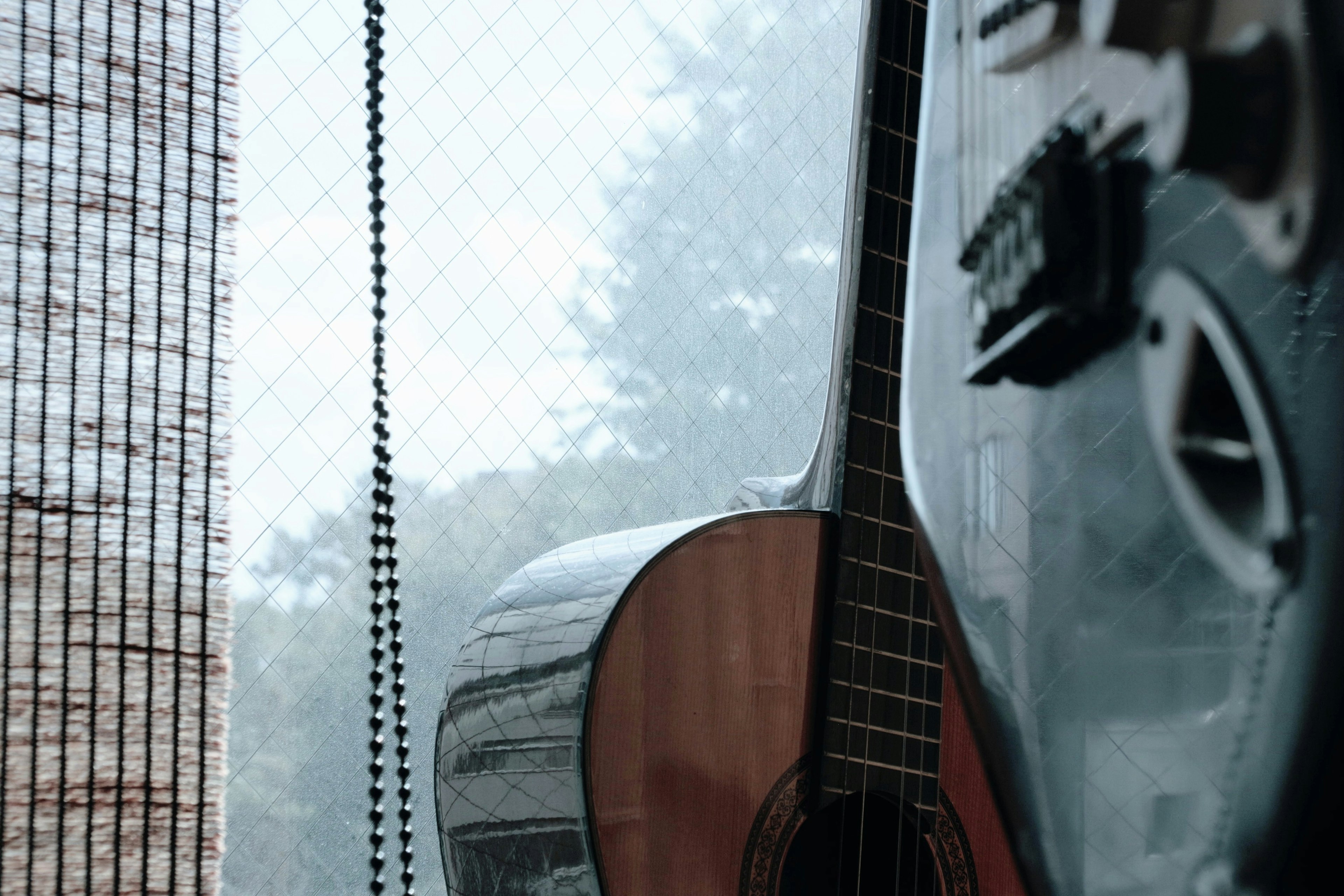 A quiet interior featuring an acoustic guitar and part of an electric guitar near a window