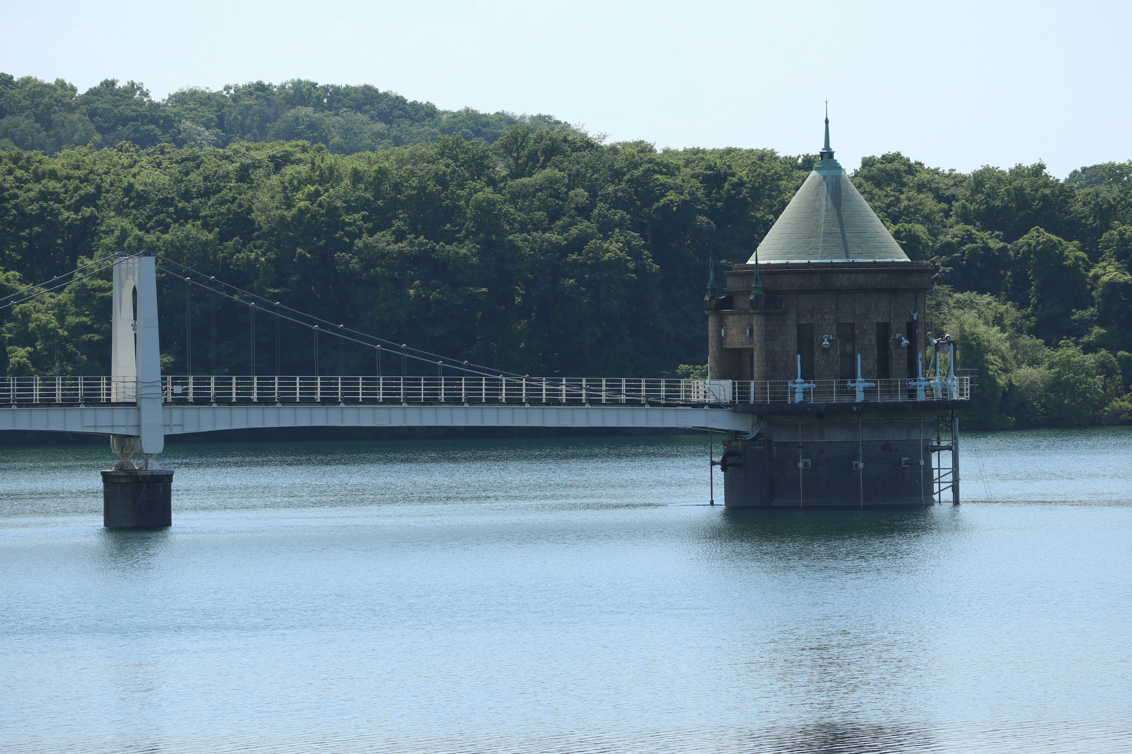 Una hermosa torre de agua y un puente colgante sobre un lago tranquilo