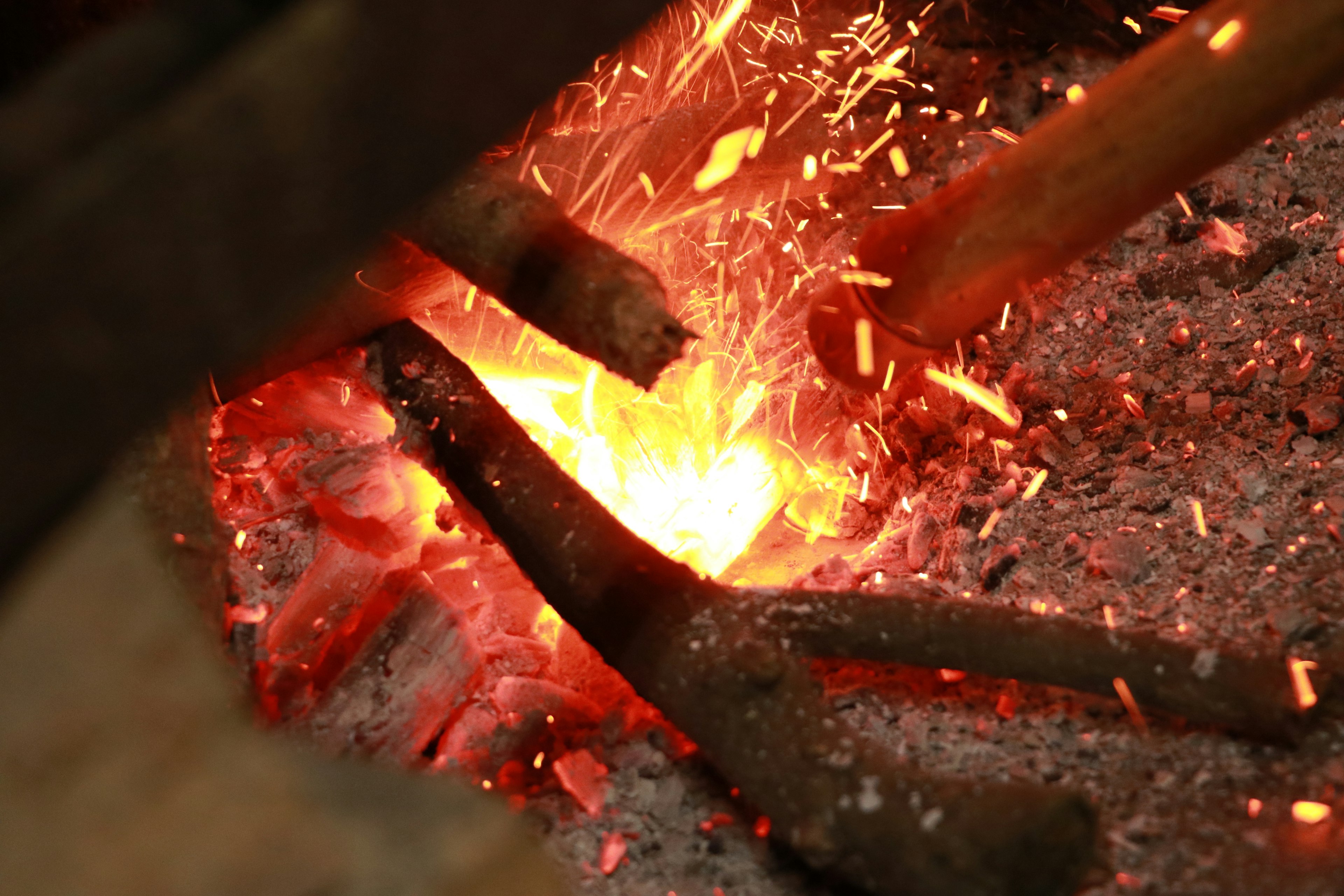 Metal rods glowing in red-hot embers with flying sparks