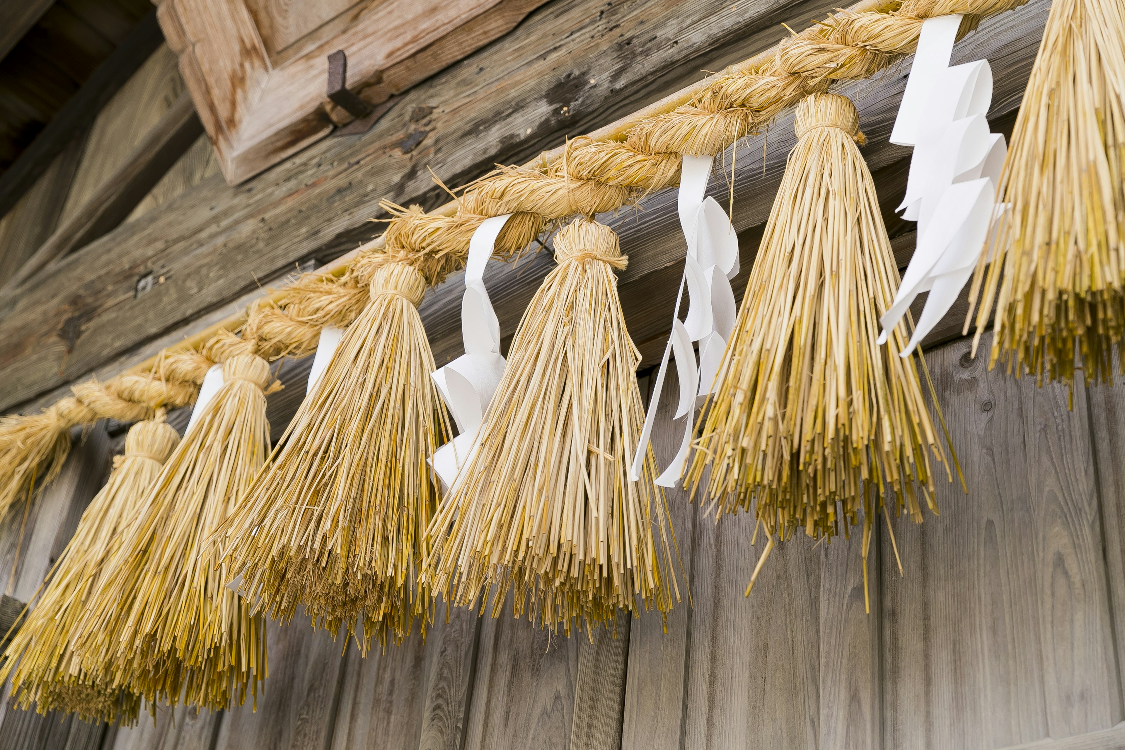 Decorative bundles made of straw hanging on a wooden wall